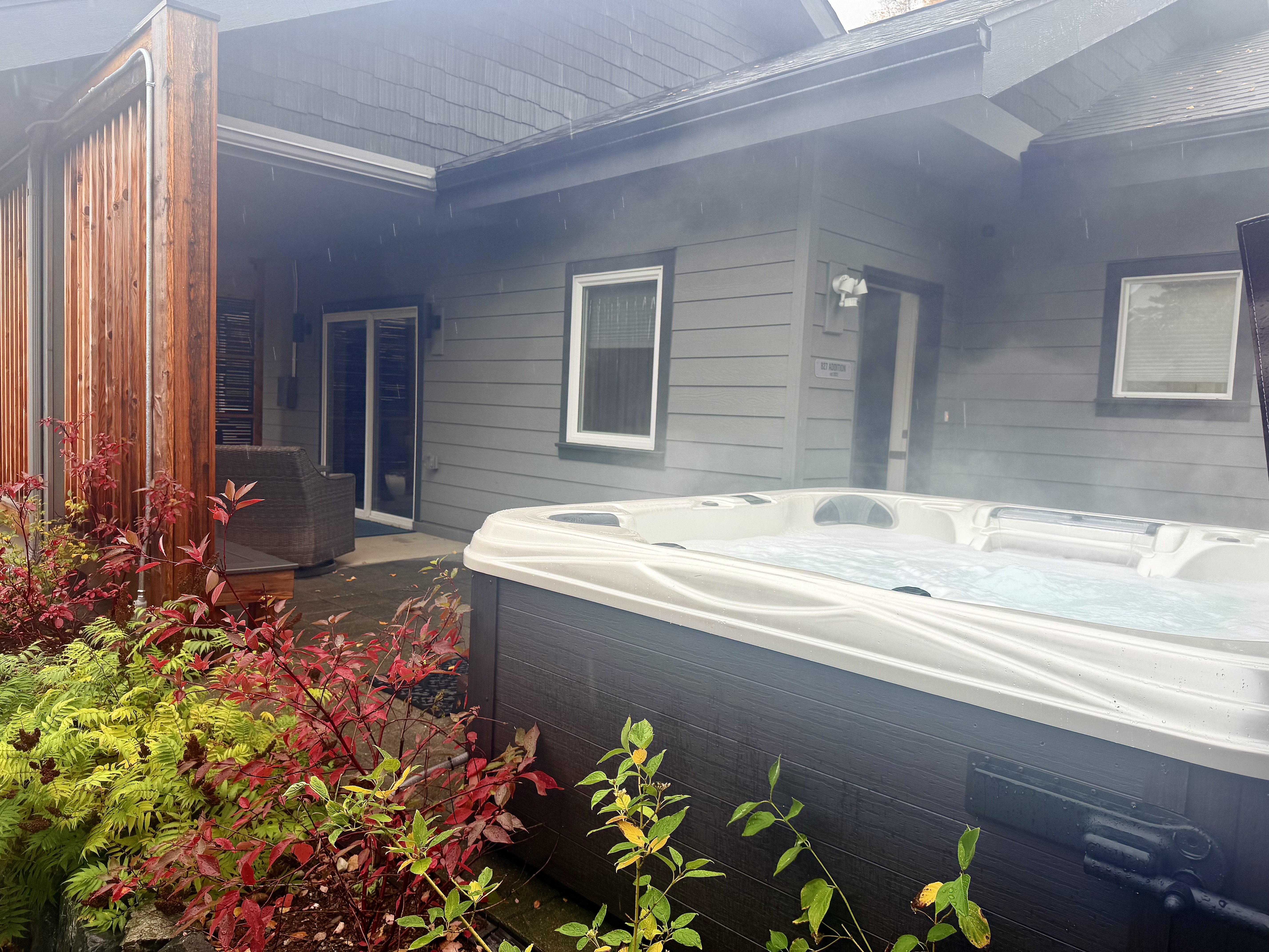 Private outdoor hot tub with cozy patio seating and lush landscaping
