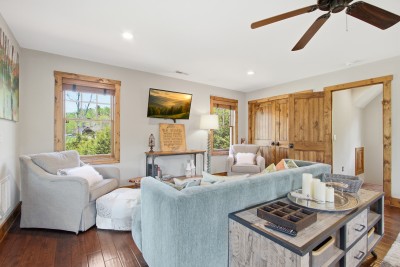 Bright rustic lounge with plush seating, HDTV, and wooded views