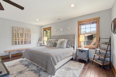 Sunny rustic-chic king suite with hardwood floors, plush rug, and views