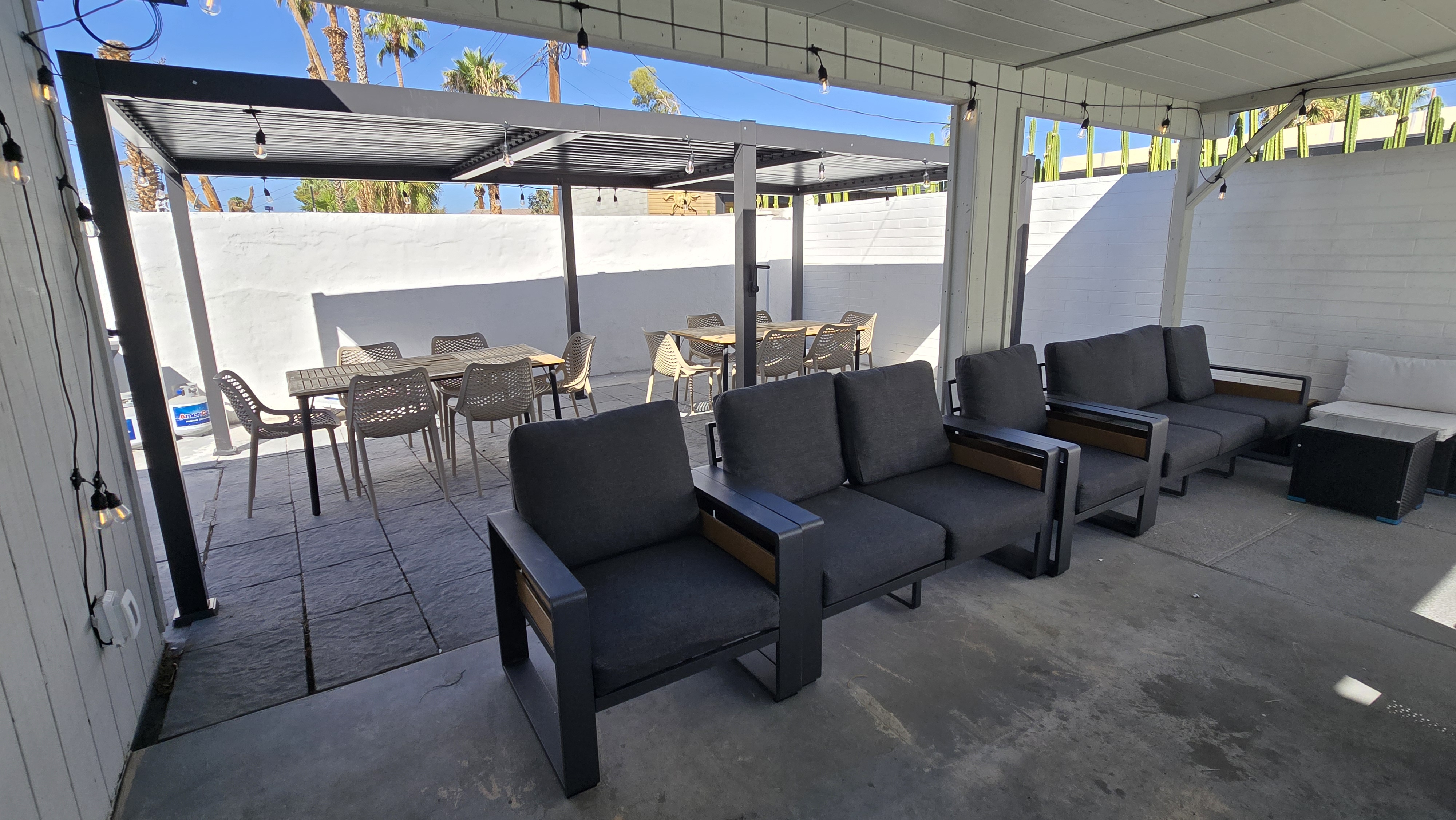 Covered patio with lounge seating, string lights, and outdoor dining