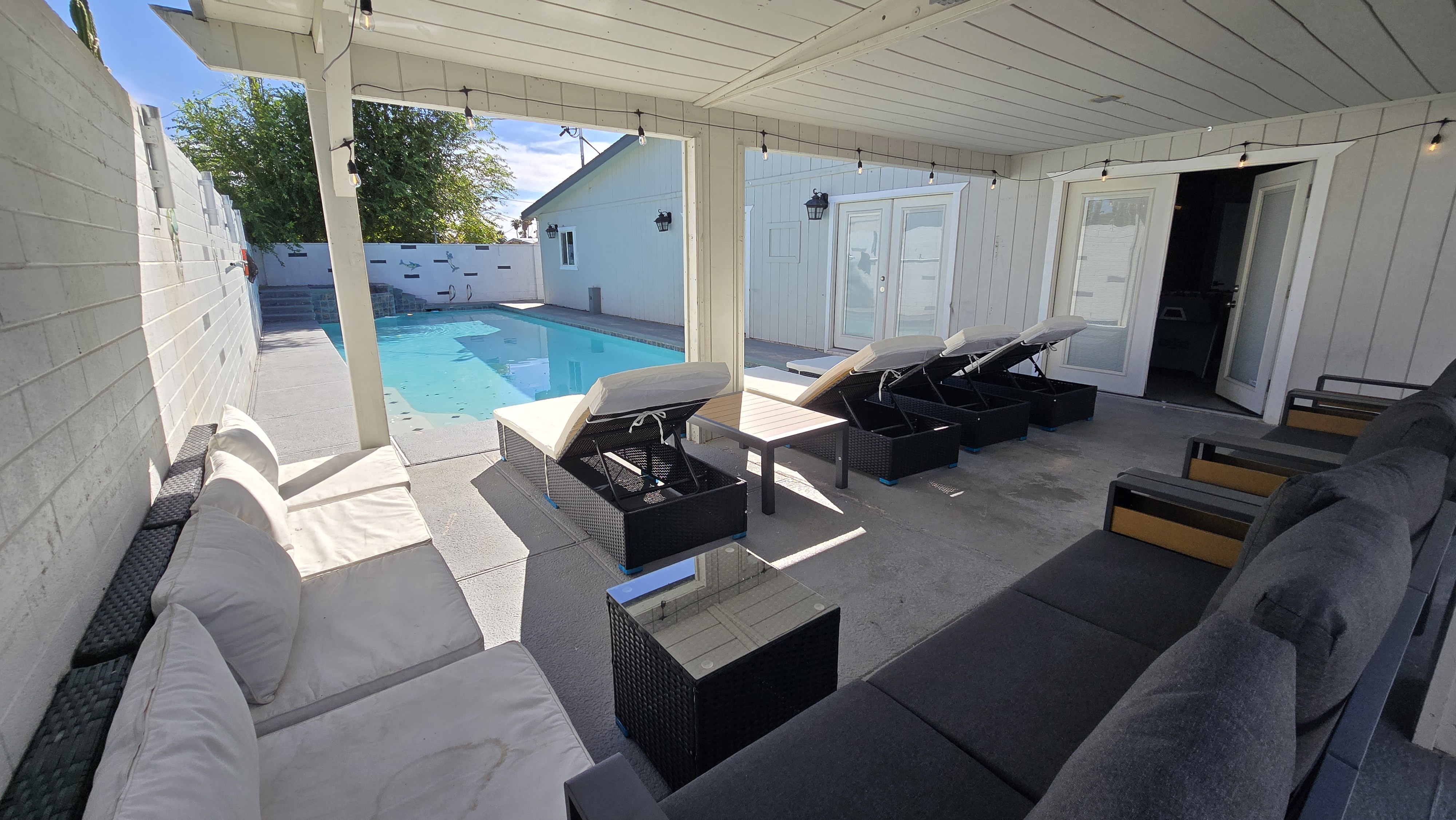 Covered poolside patio with loungers, cozy seating, and private pool