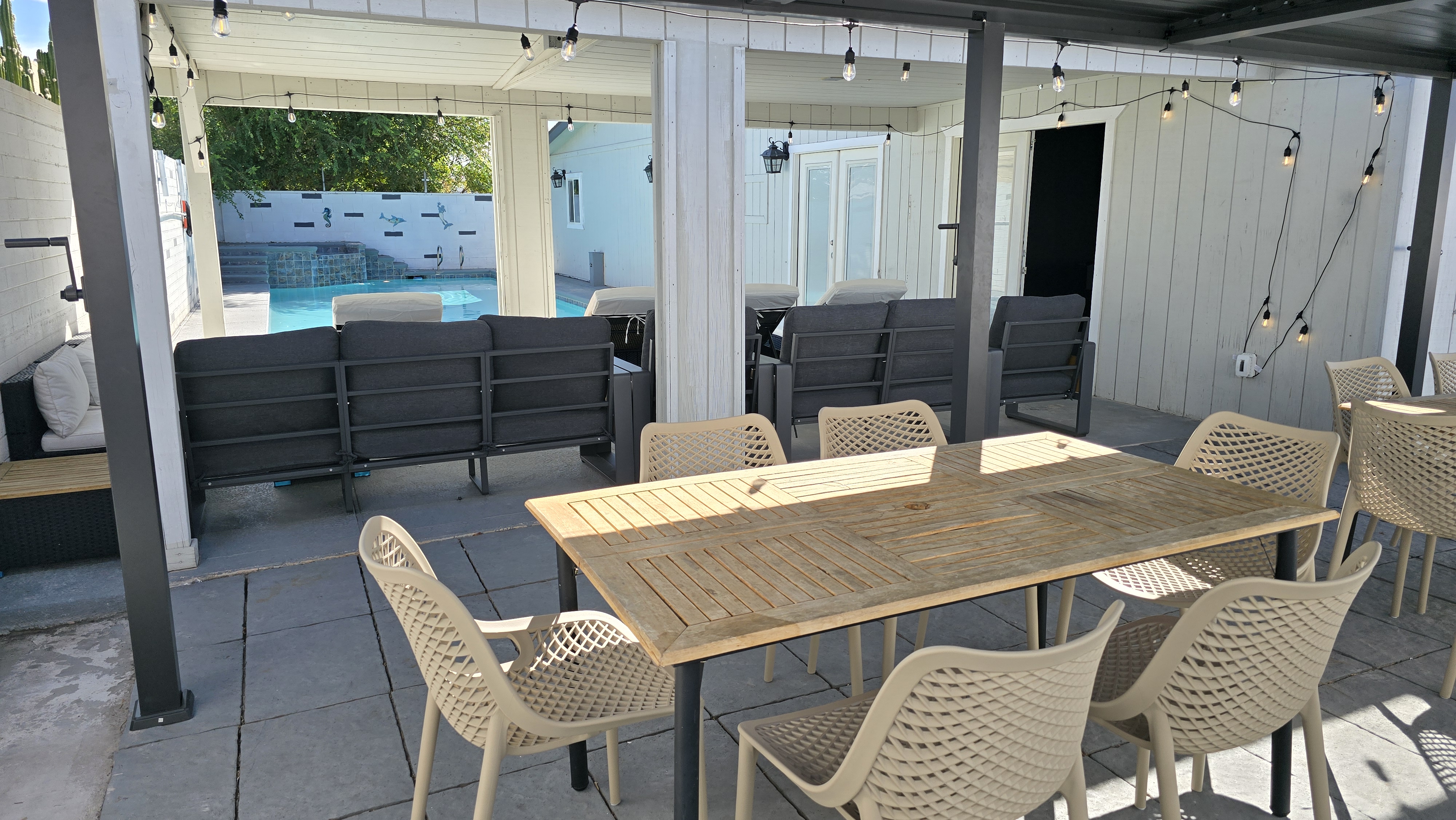 Covered patio with dining, lounge seating, and easy pool access