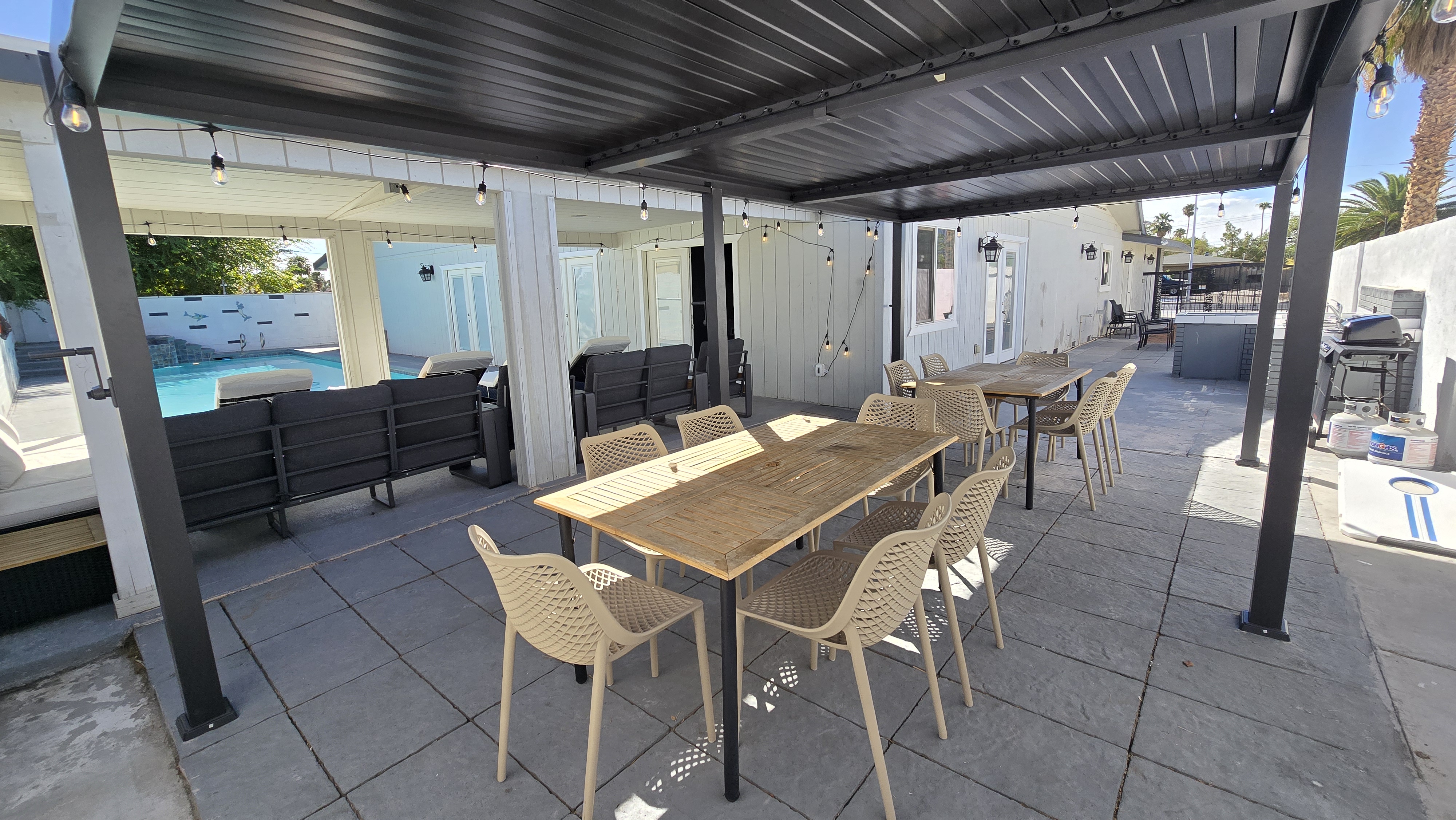 Covered patio with dining for groups, pool access, and grill area