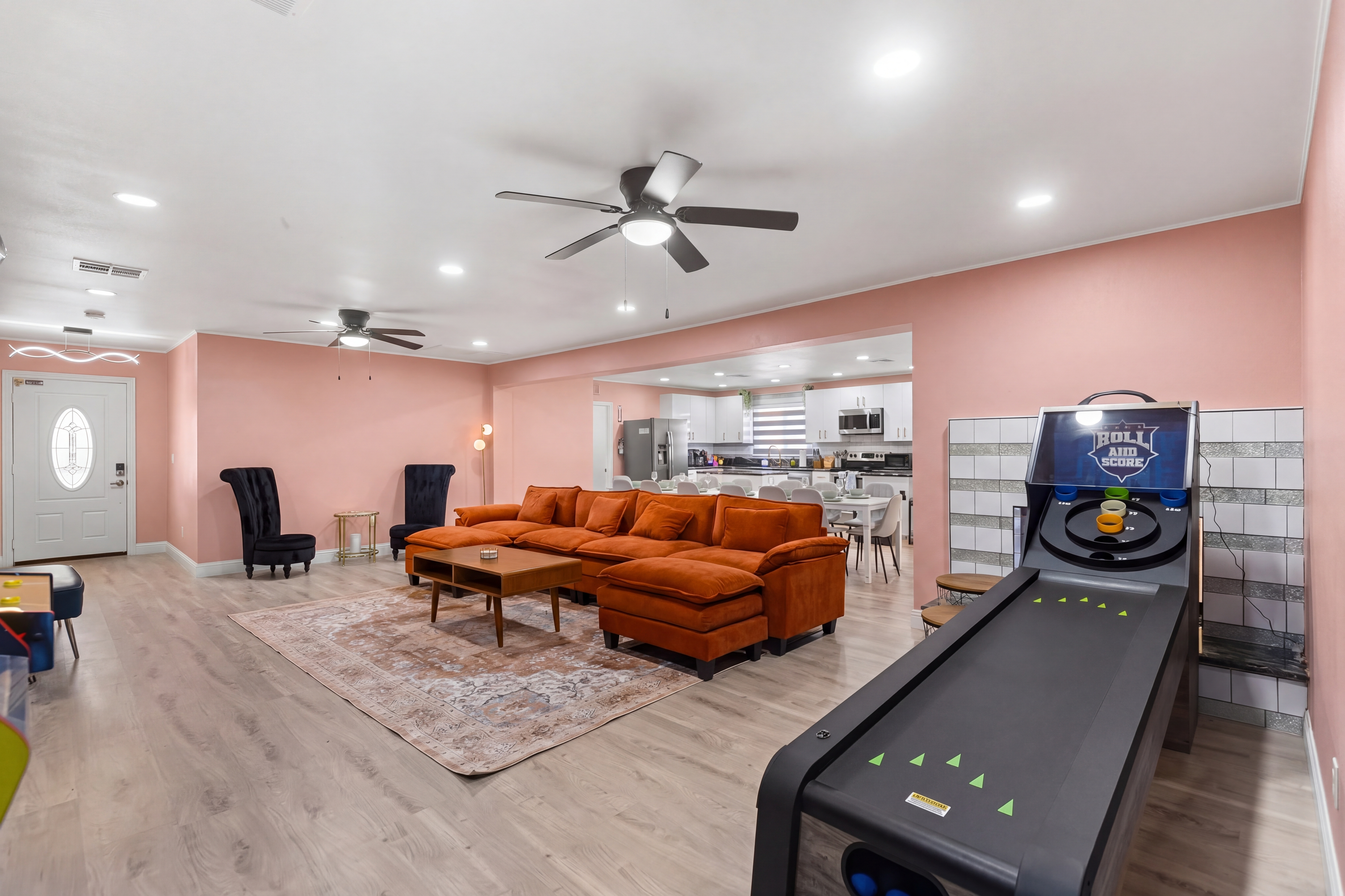 Spacious lounge with large sectional, open kitchen, and fun skee-ball game