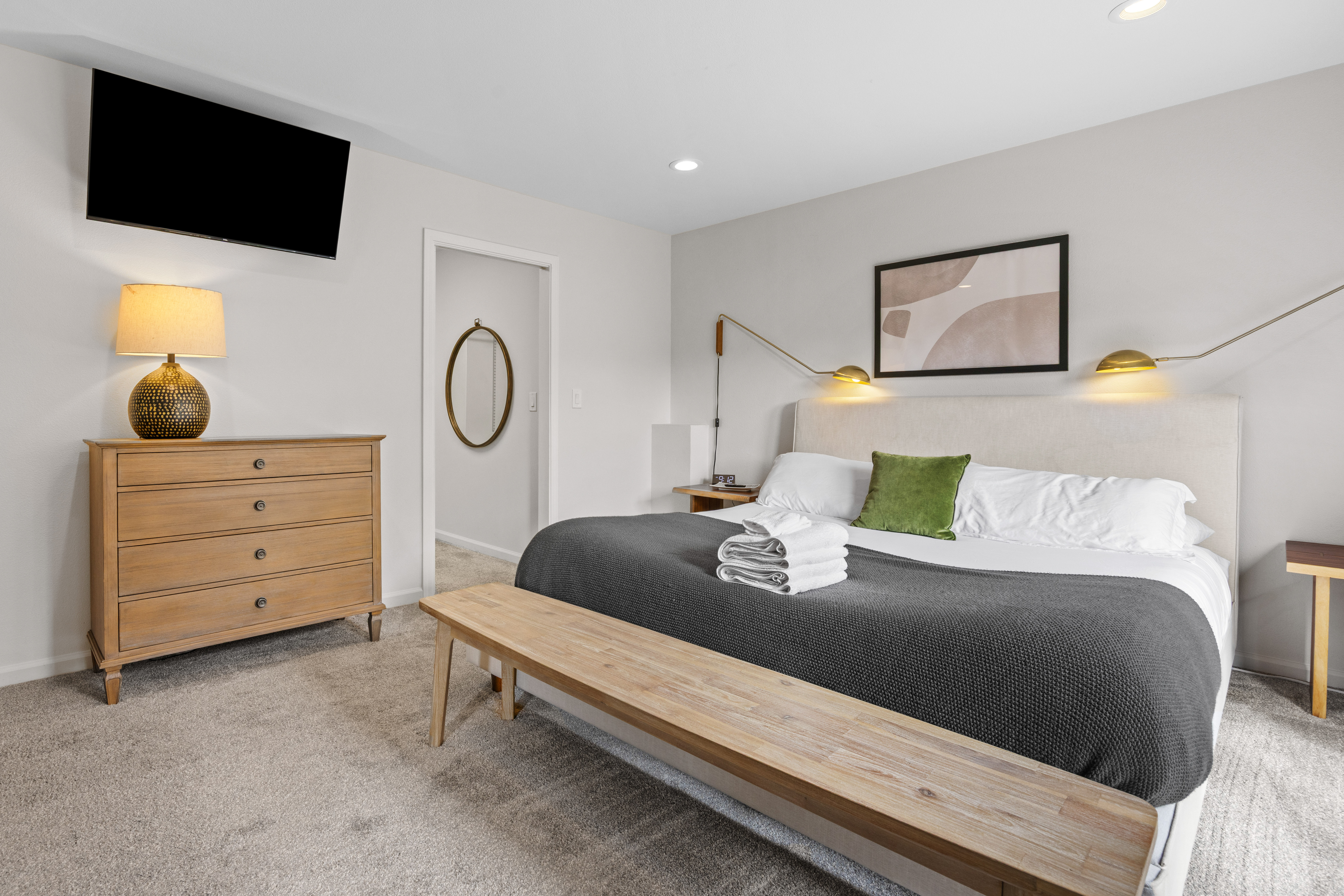 Bright modern bedroom with king bed, TV, and stylish cozy touches