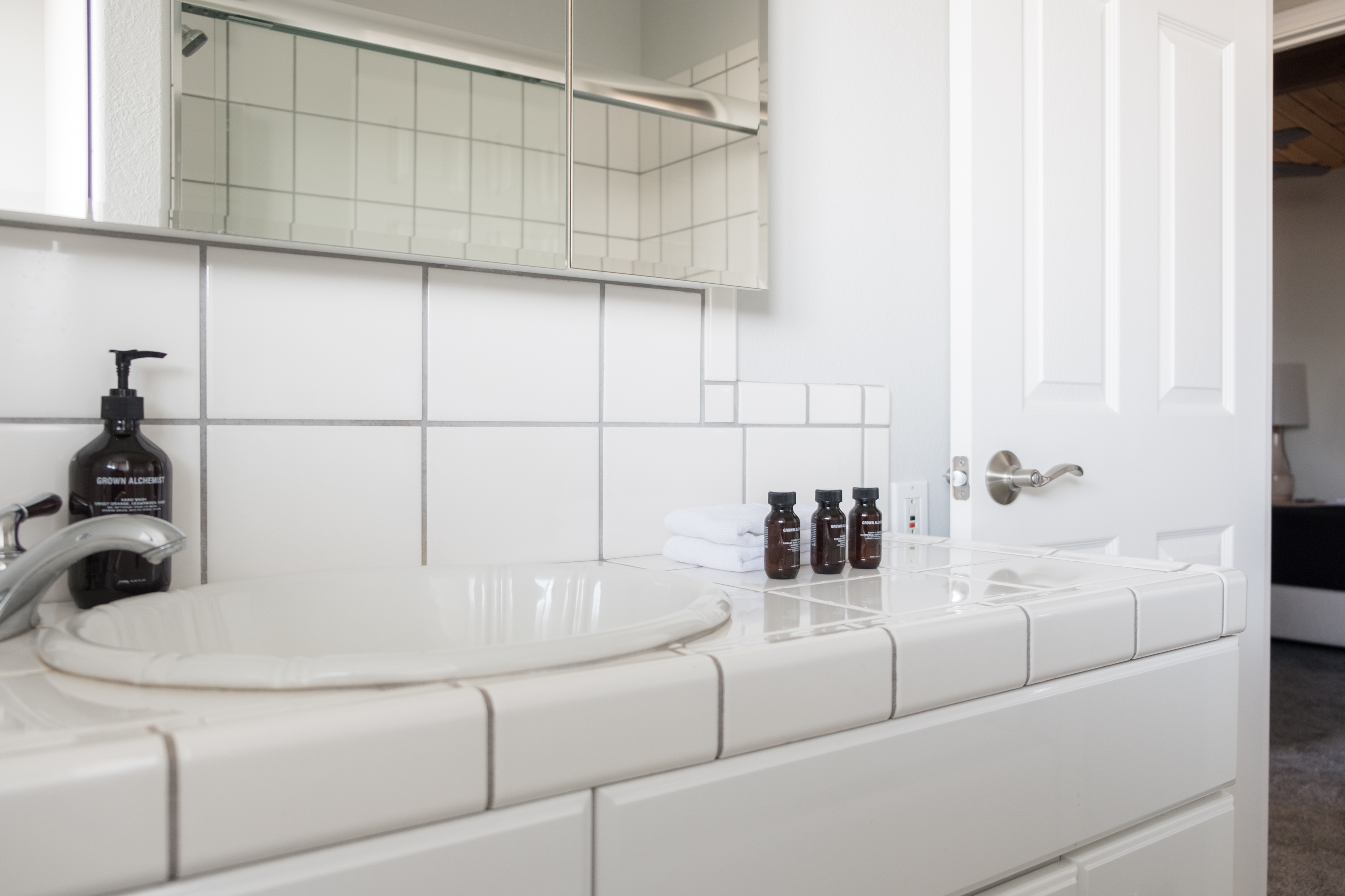 Bright tiled bathroom vanity with guest toiletries and a clean, airy feel