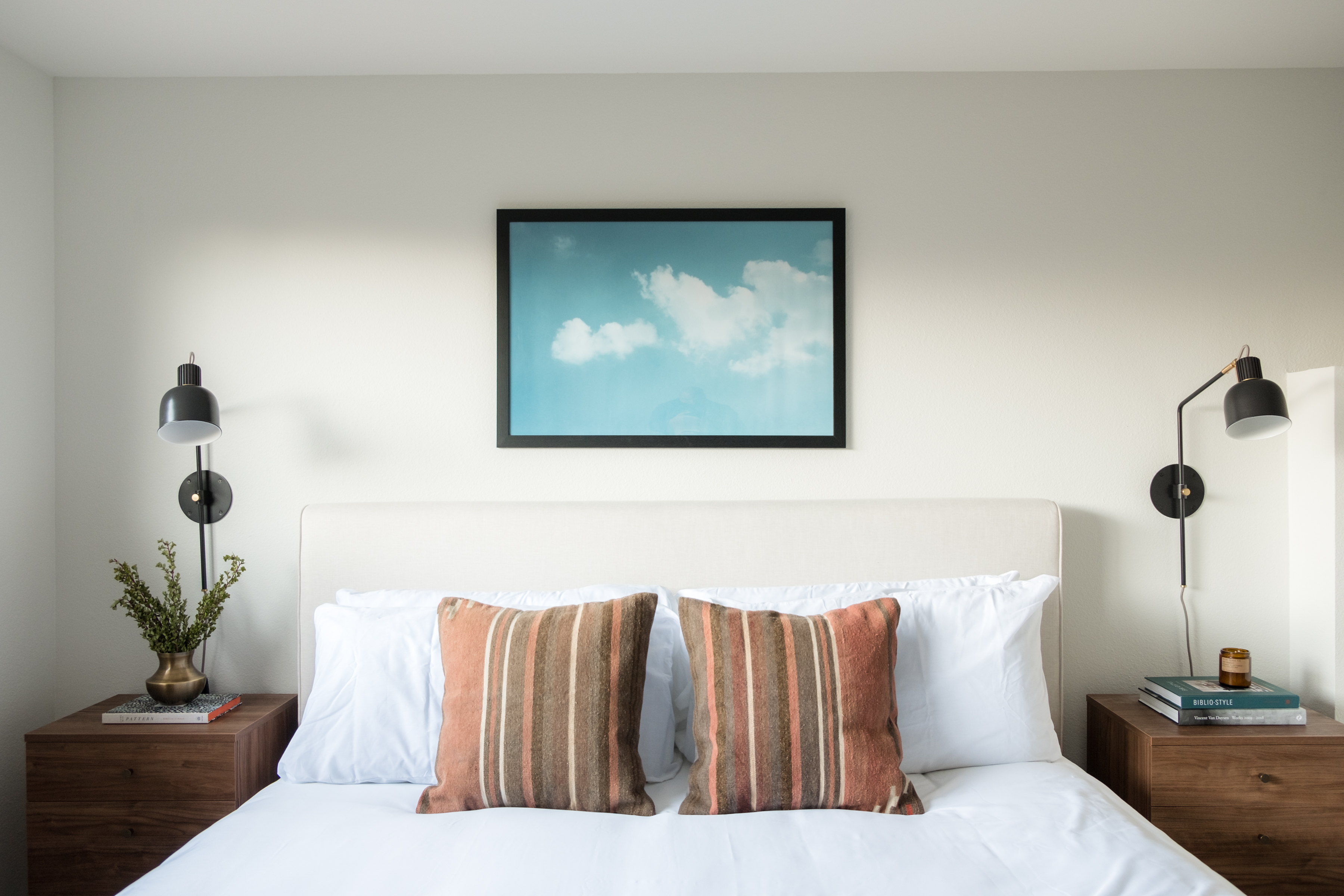 Bright, modern bedroom with plush bedding and stylish bedside lighting