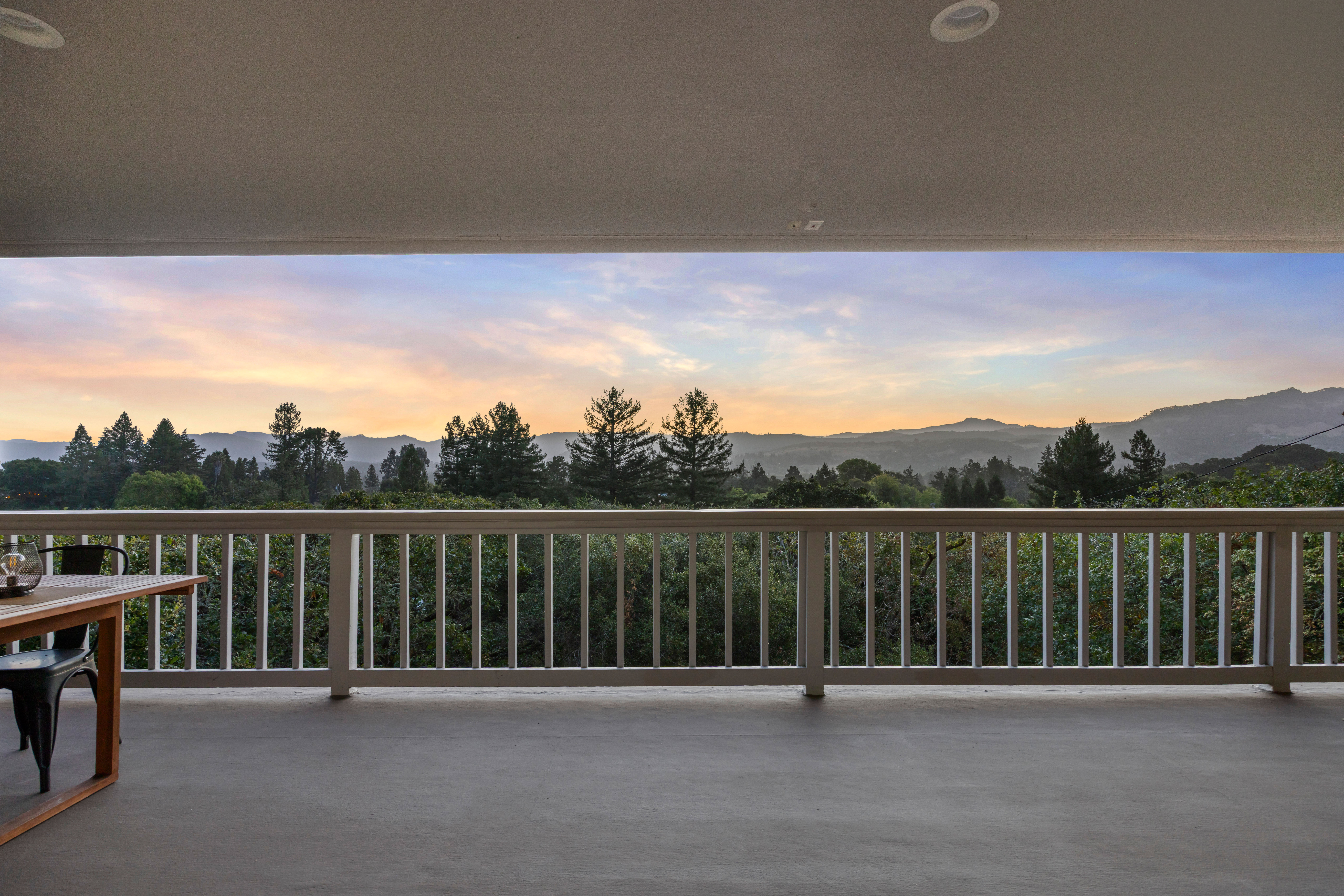 Covered balcony with sweeping sunset views of trees, hills, and mountains