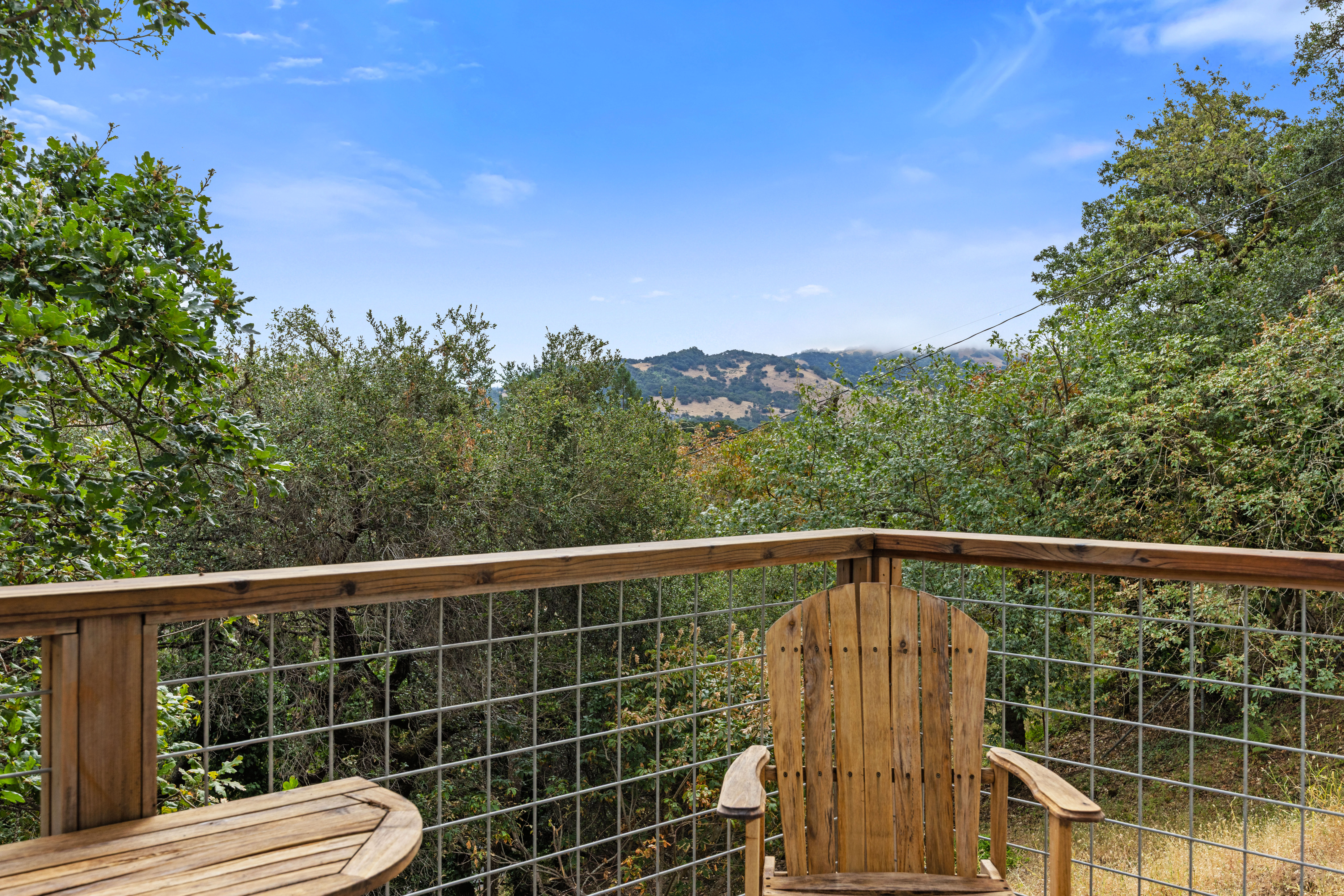 Peaceful treetop deck with hillside views and a cozy rustic chair