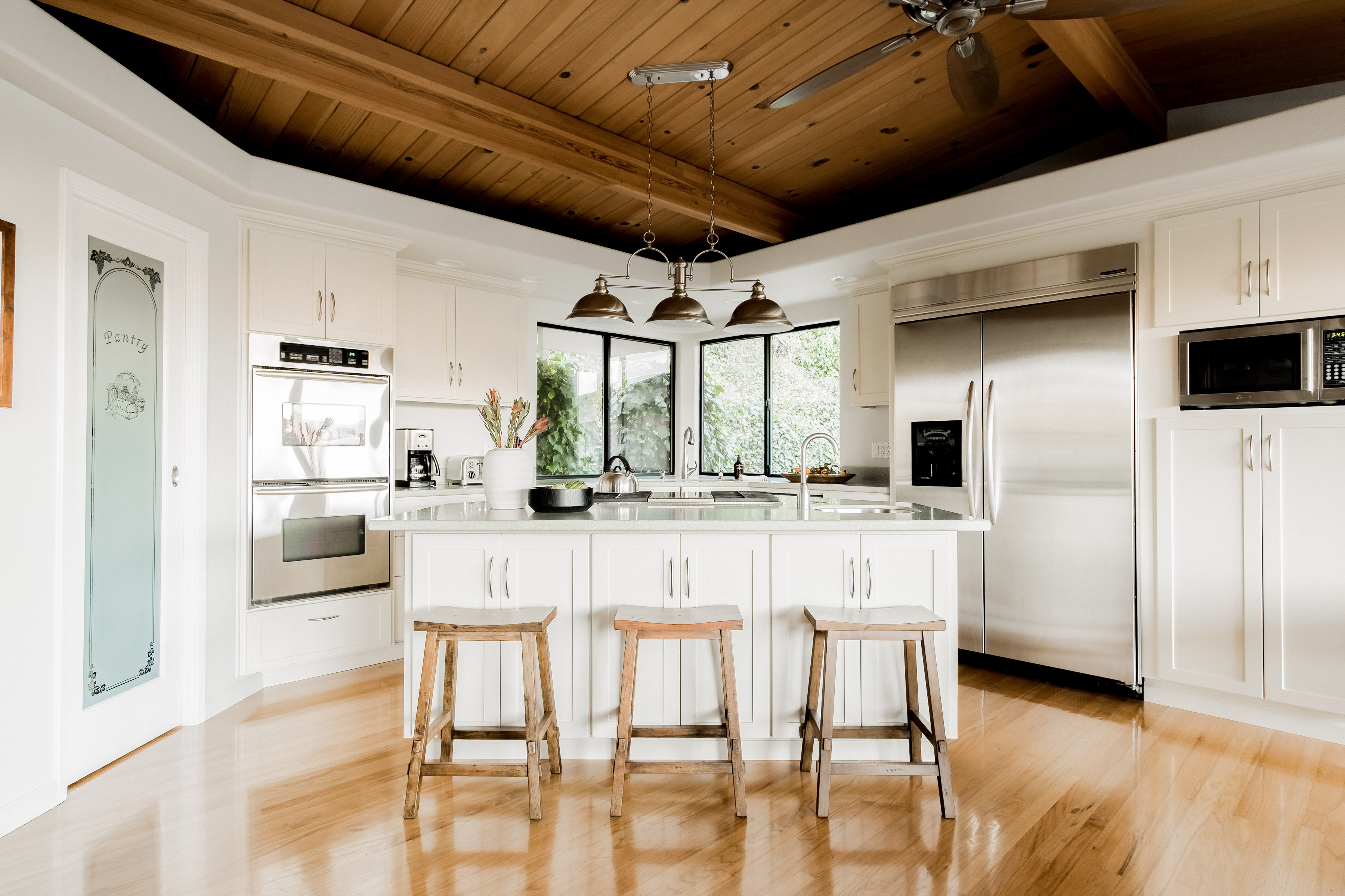 Bright gourmet kitchen with island seating and warm wood ceiling