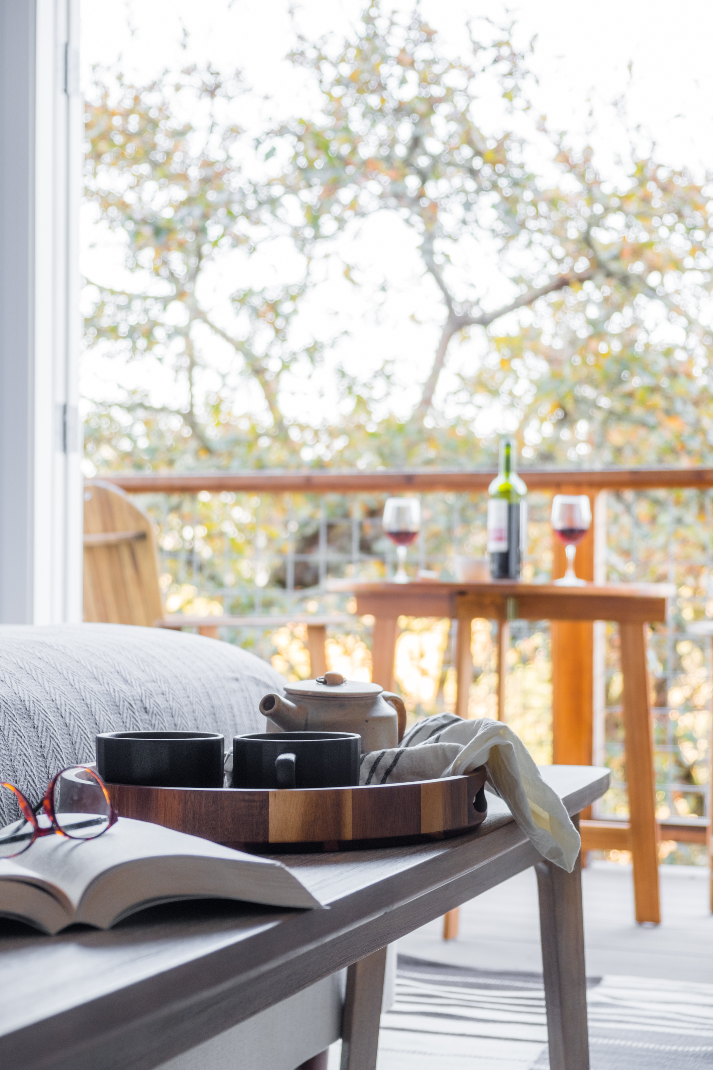 Cozy lounge and private deck with tree views, tea service, and wine setup