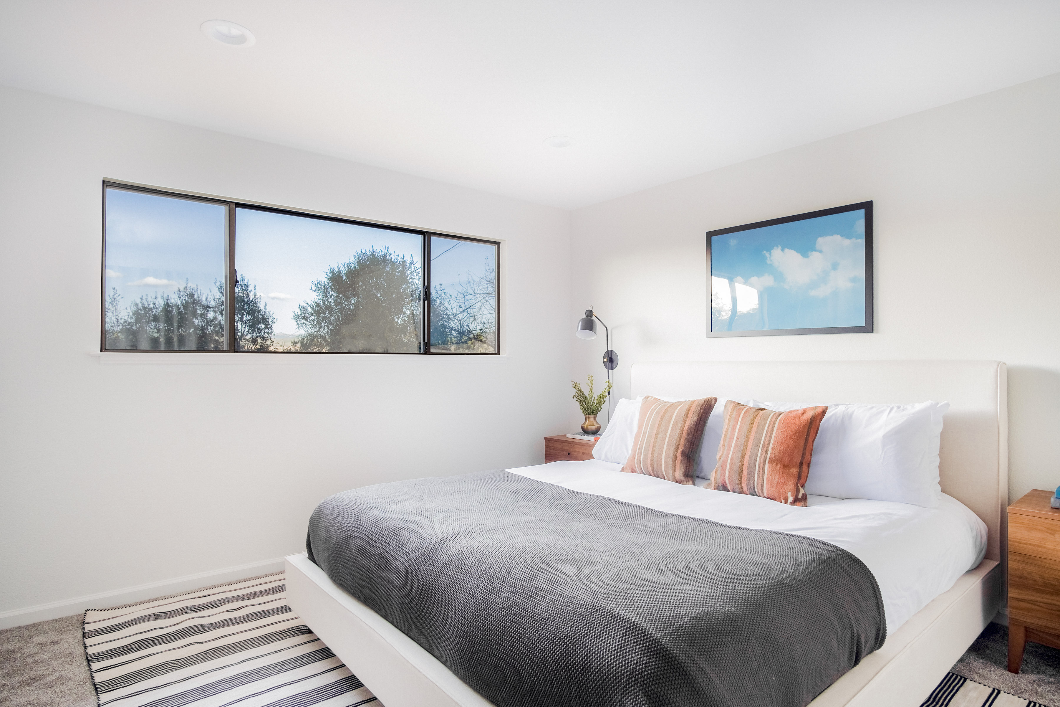 Bright, serene bedroom with king bed, large windows, and modern decor
