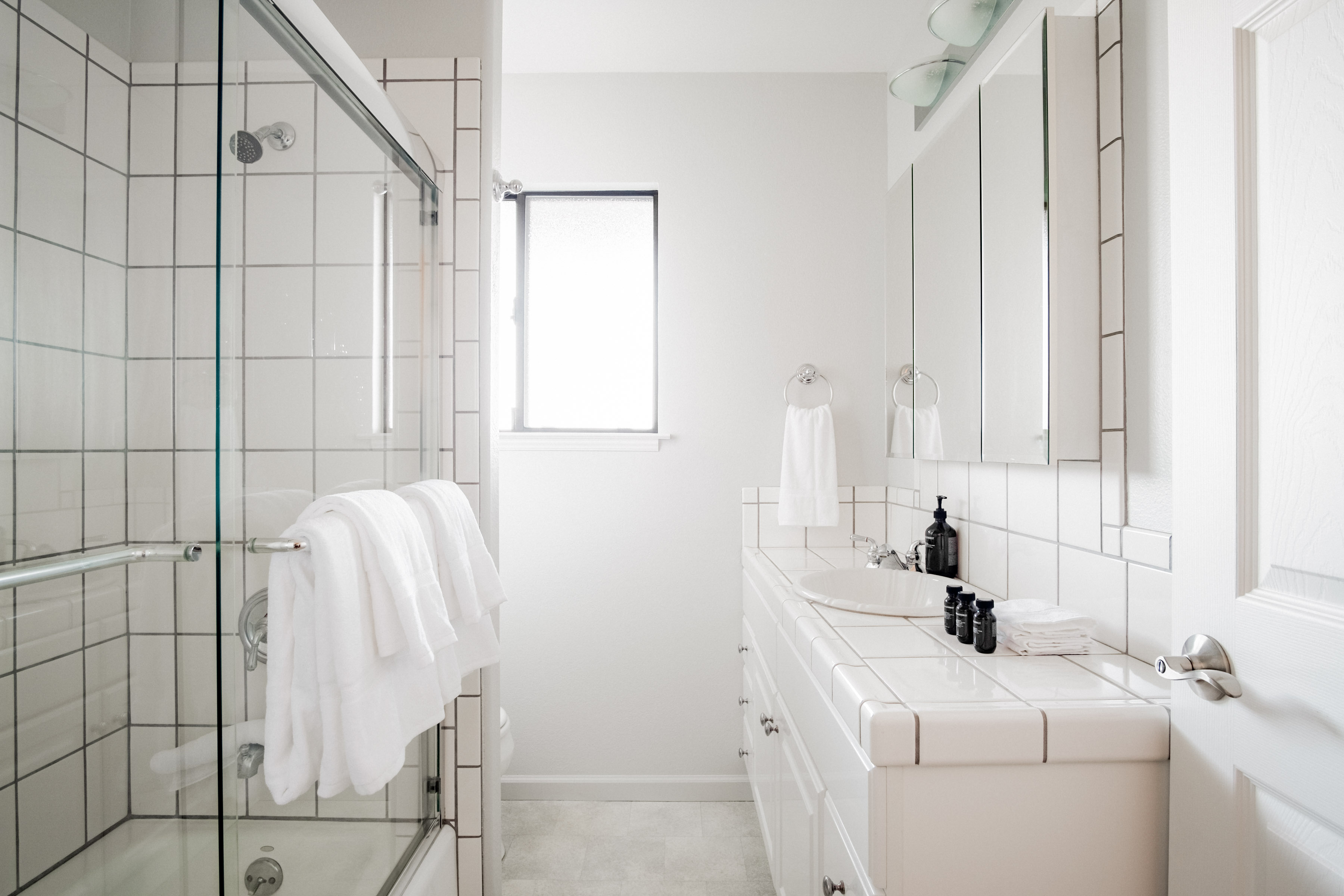 Bright spa-like bathroom with dual sinks and sleek glass shower