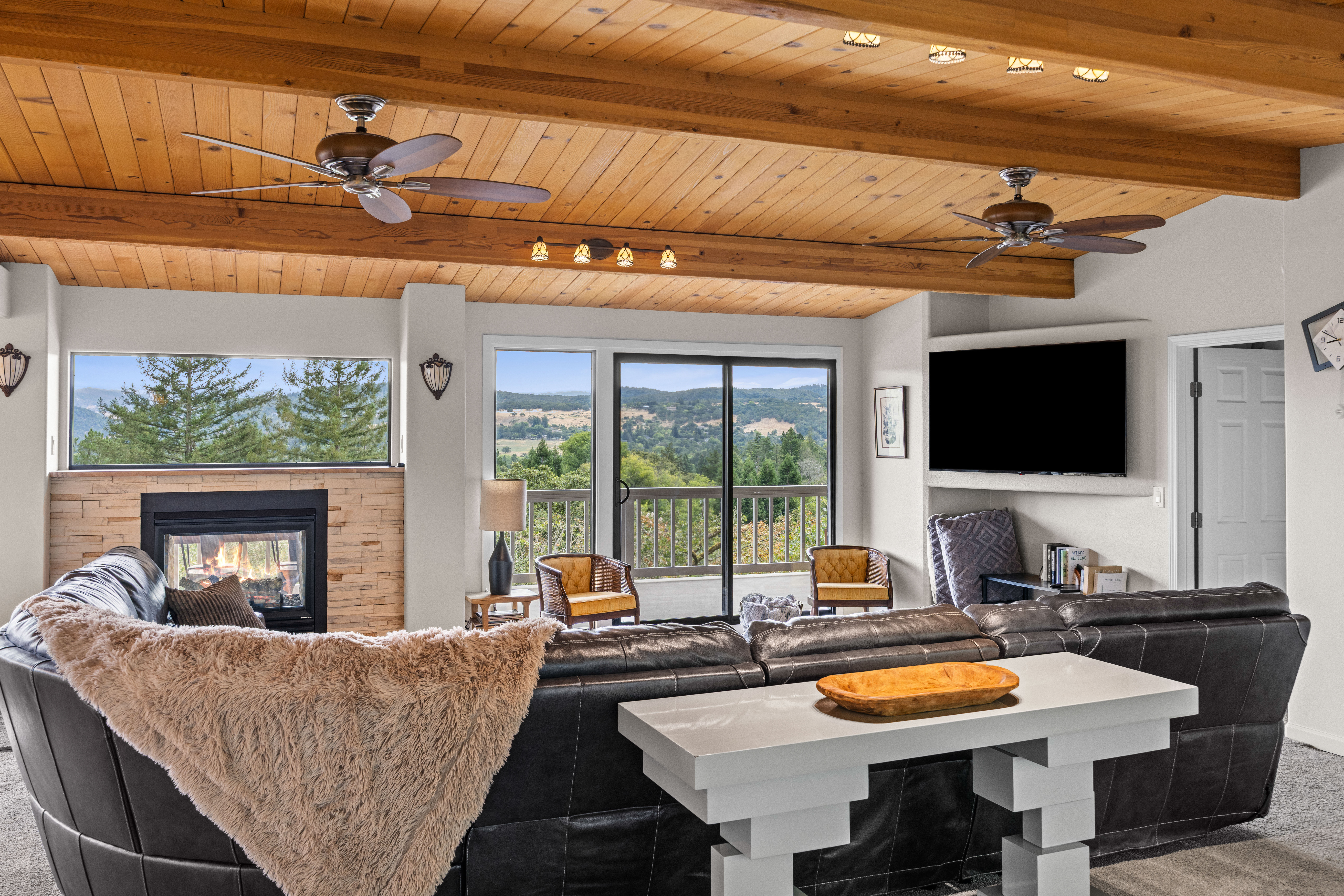 Cozy mountain-view living room with fireplace, TV, and sunny deck access