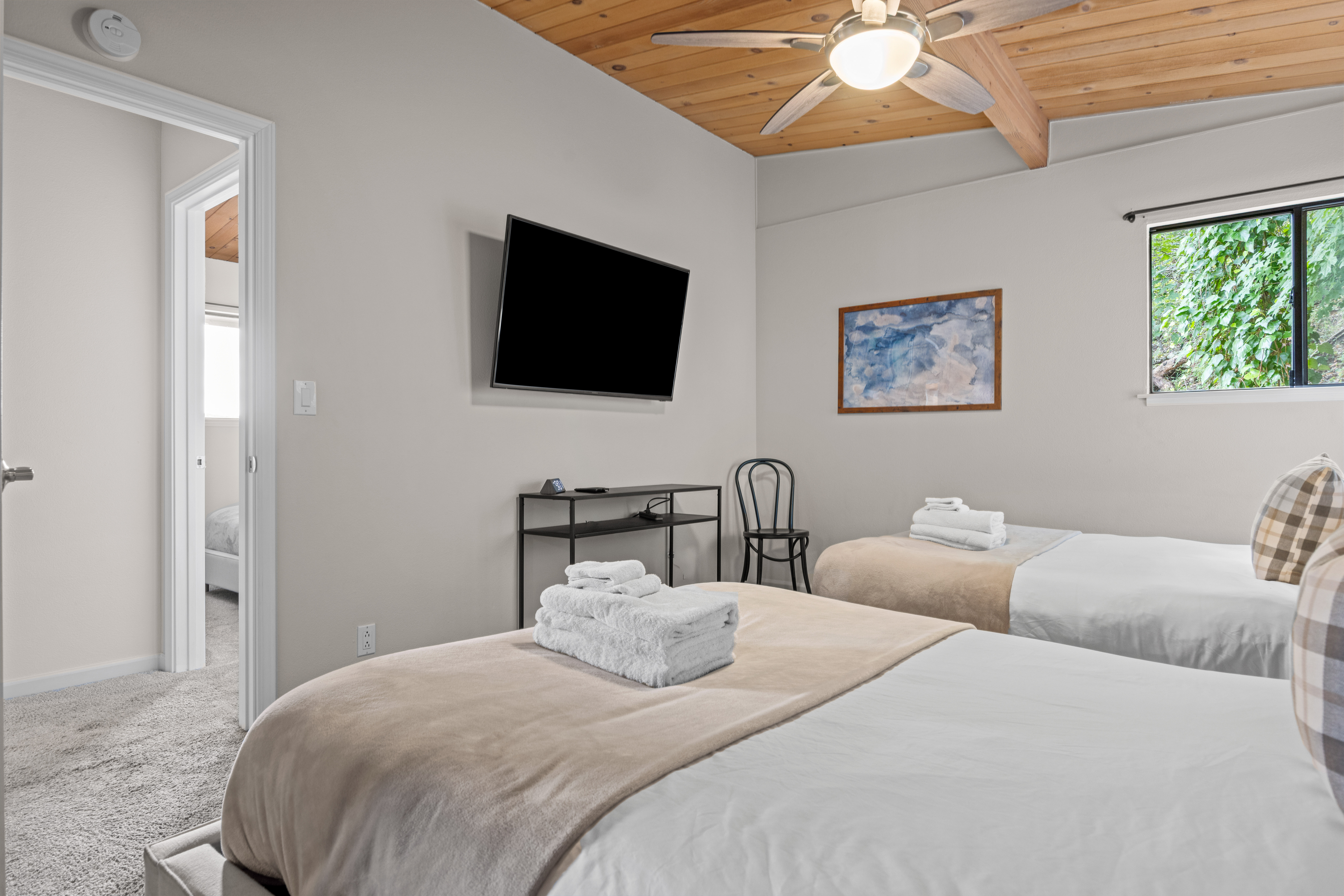 Bright double bedroom with TV, cozy wood ceiling, and natural light