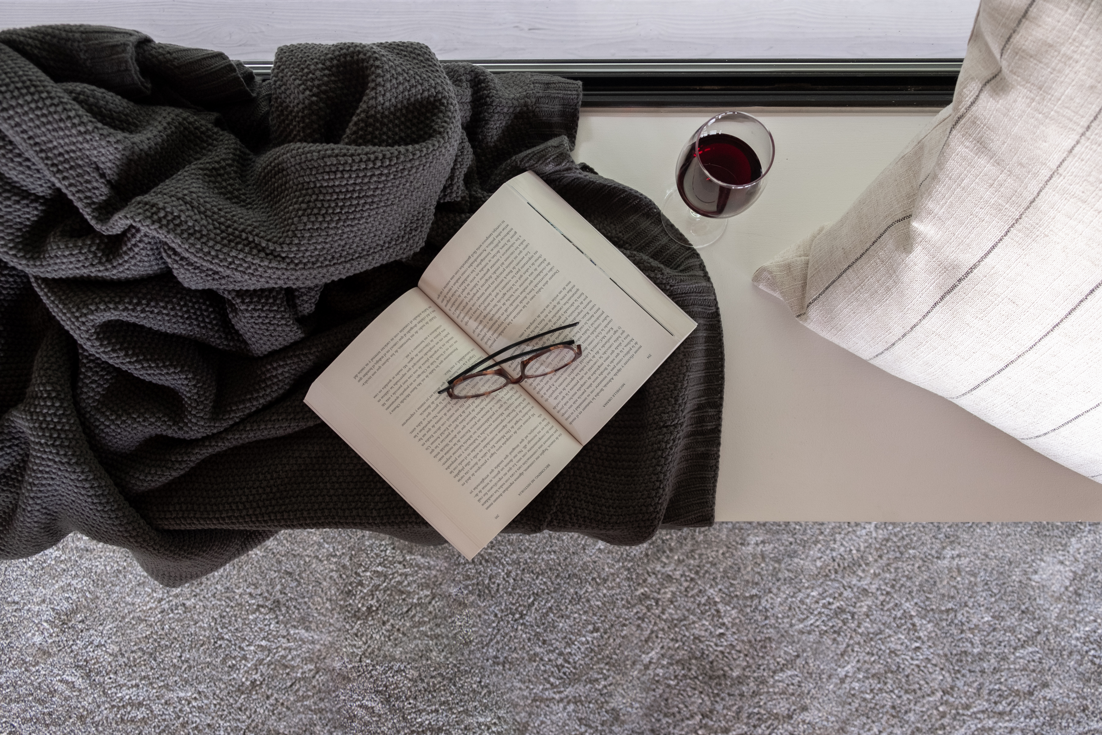 Cozy reading nook with plush textures, natural light, and a glass of wine