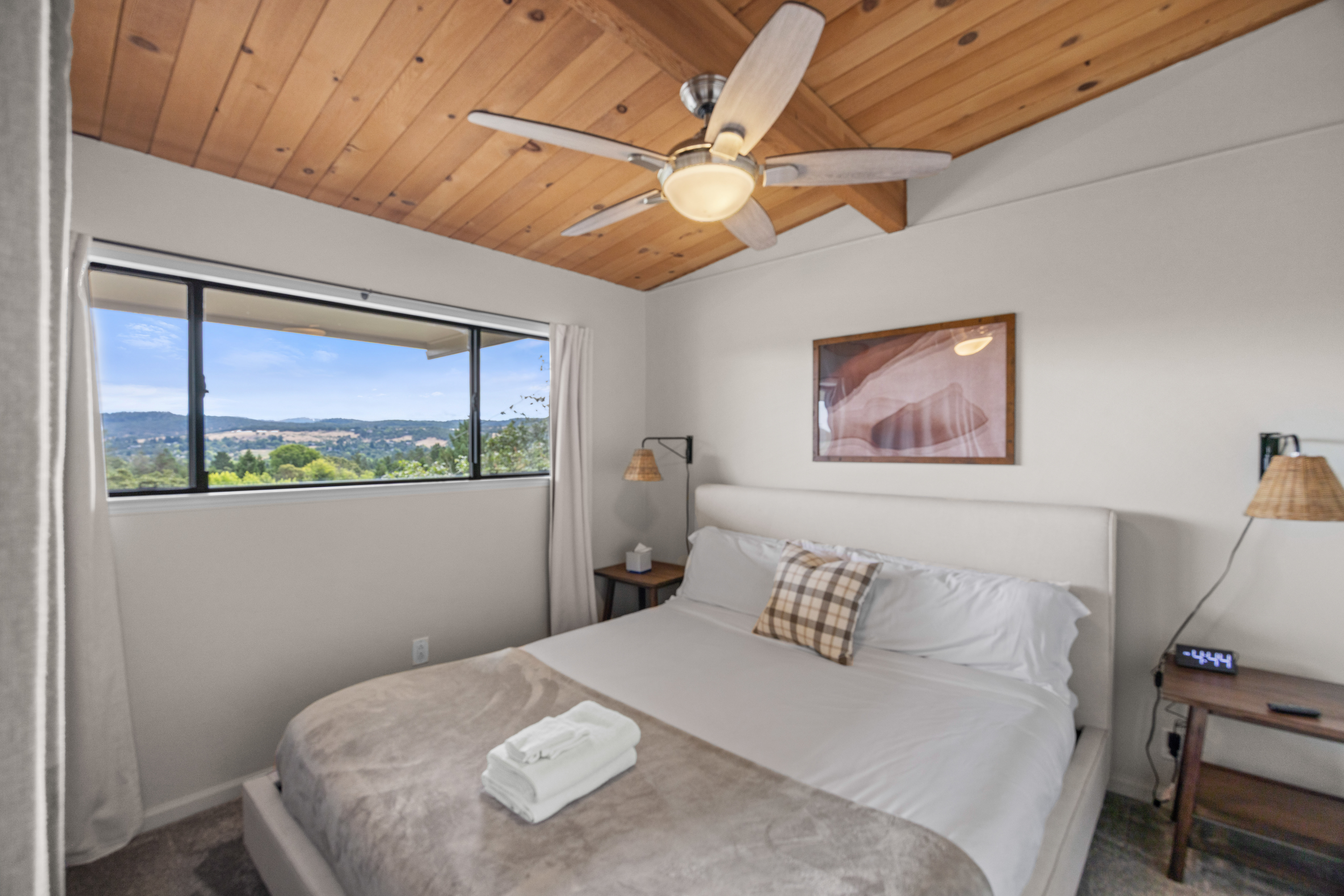 Cozy bedroom with vaulted wood ceilings and scenic hillside views