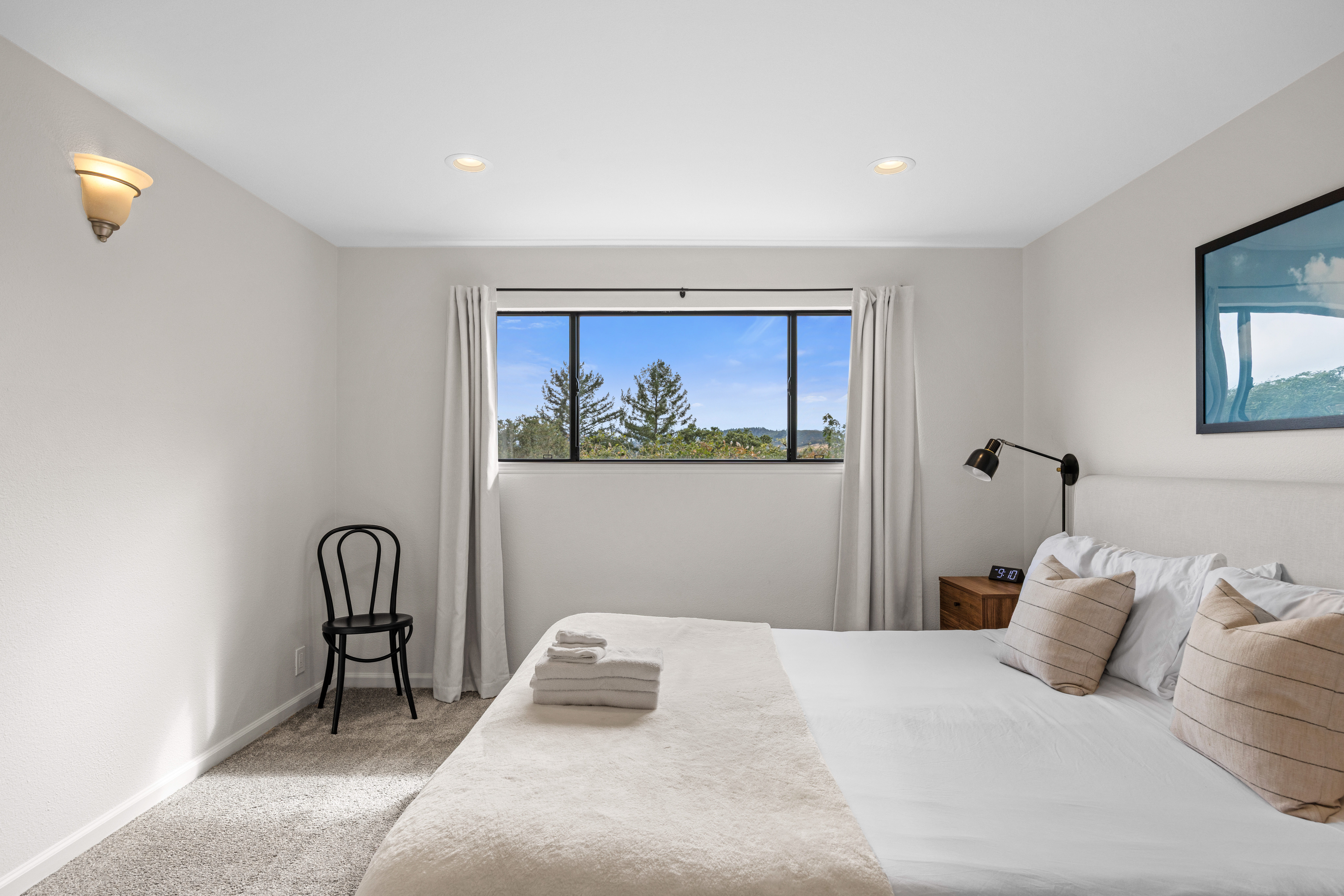 Bright, cozy bedroom with plush linens and peaceful treetop views