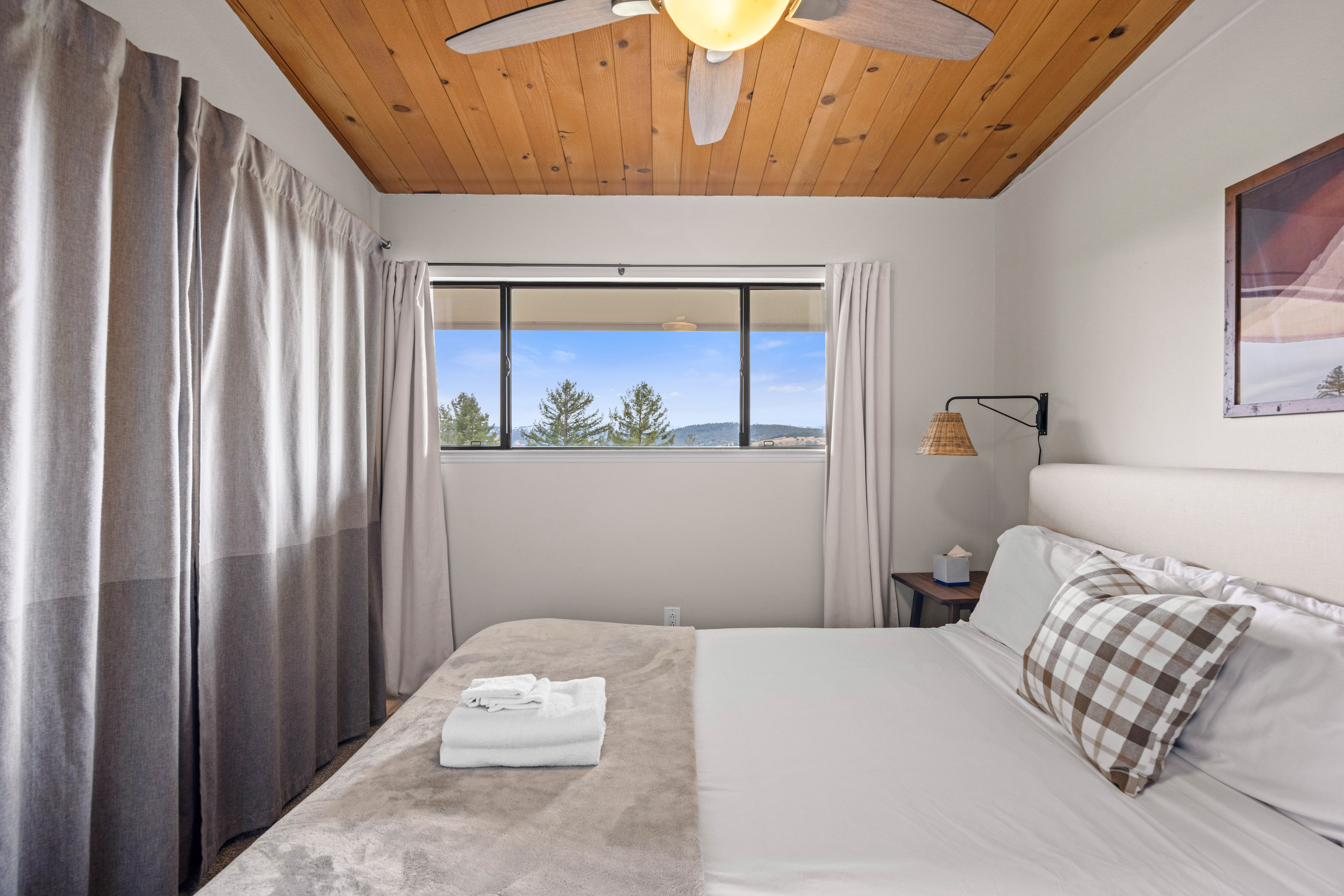 Cozy bedroom with mountain views, wood ceiling, and bright natural light
