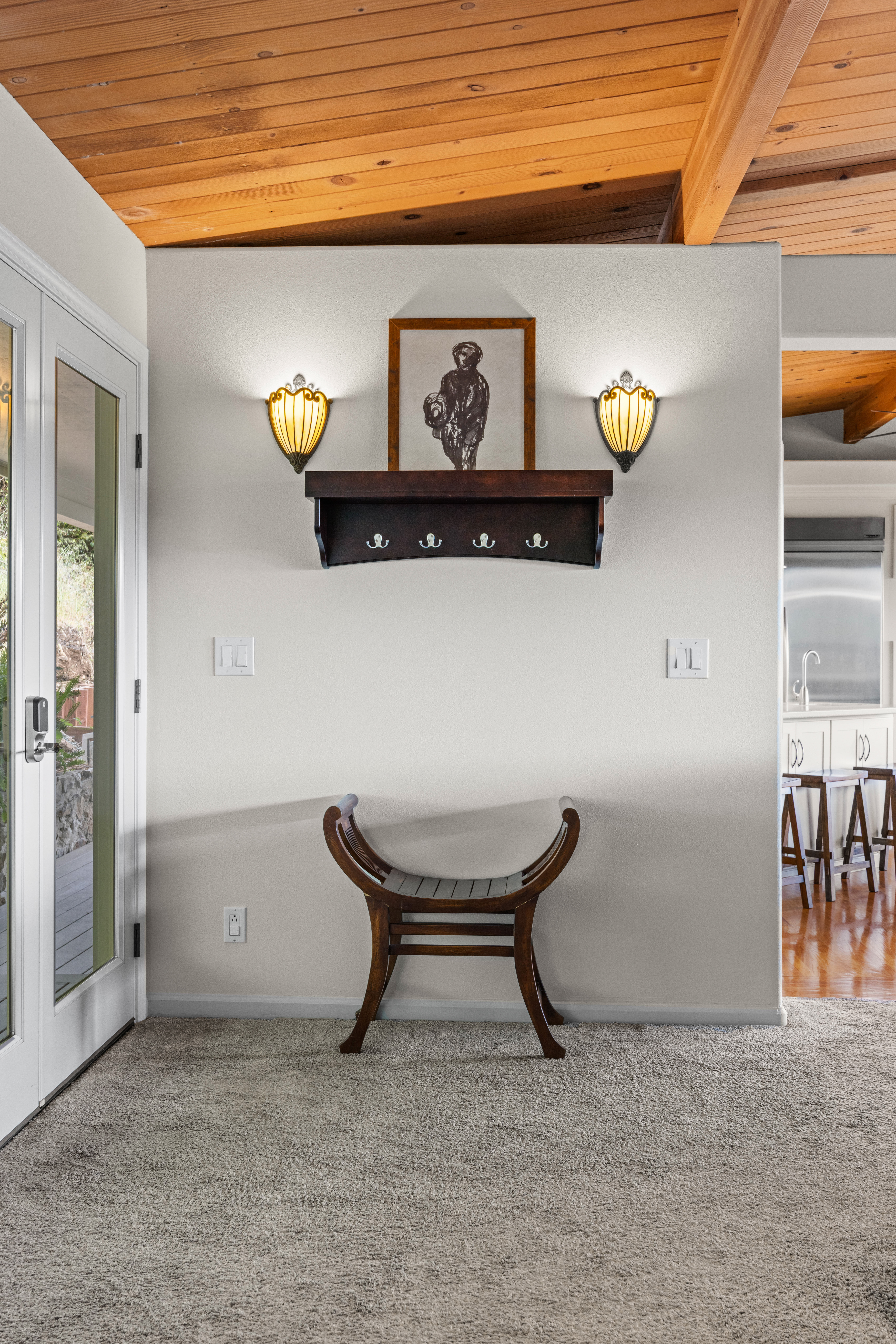 Welcoming entry nook with warm wood ceilings, bench seating, and kitchen access