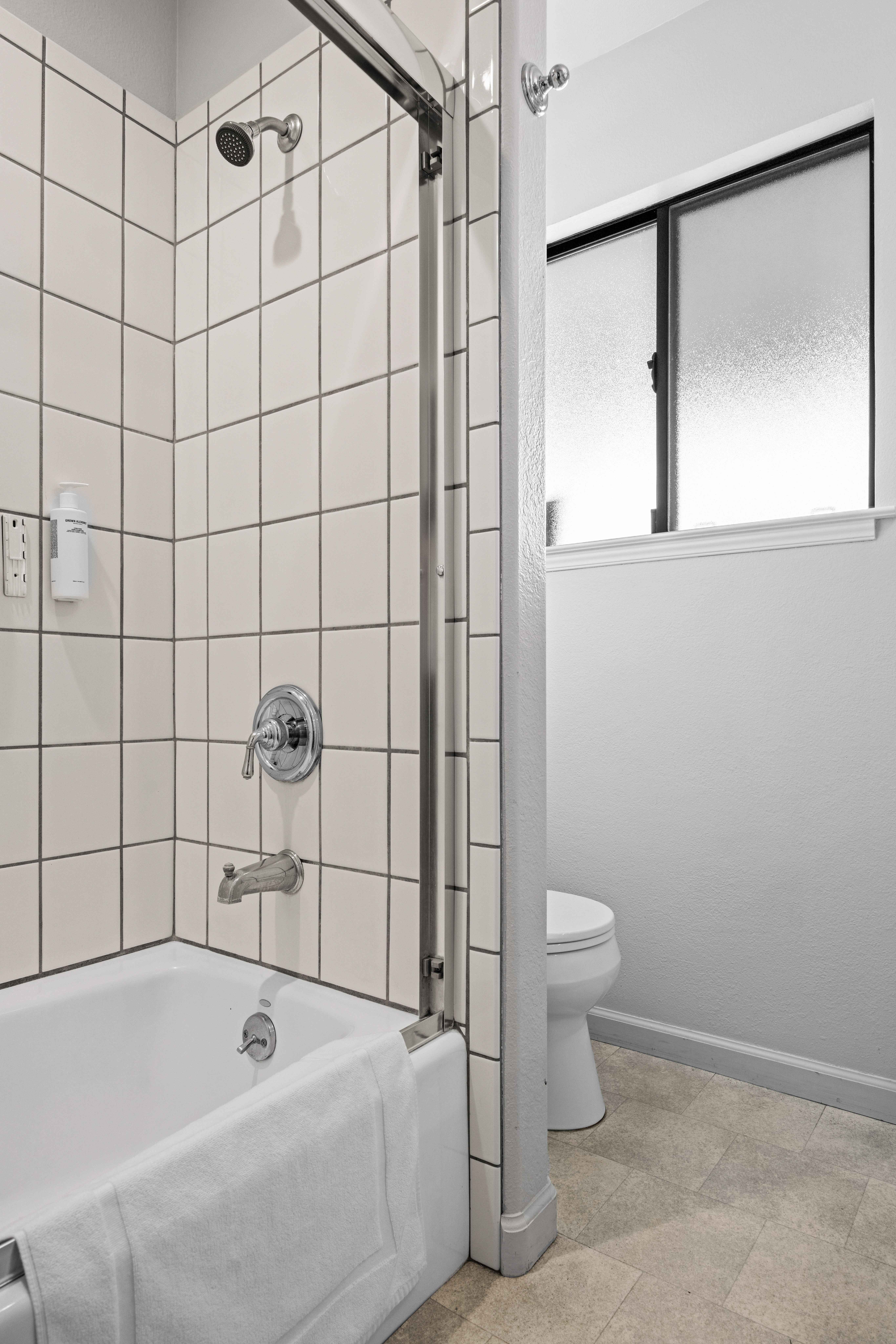 Bright tiled bathroom with tub-shower combo and natural light