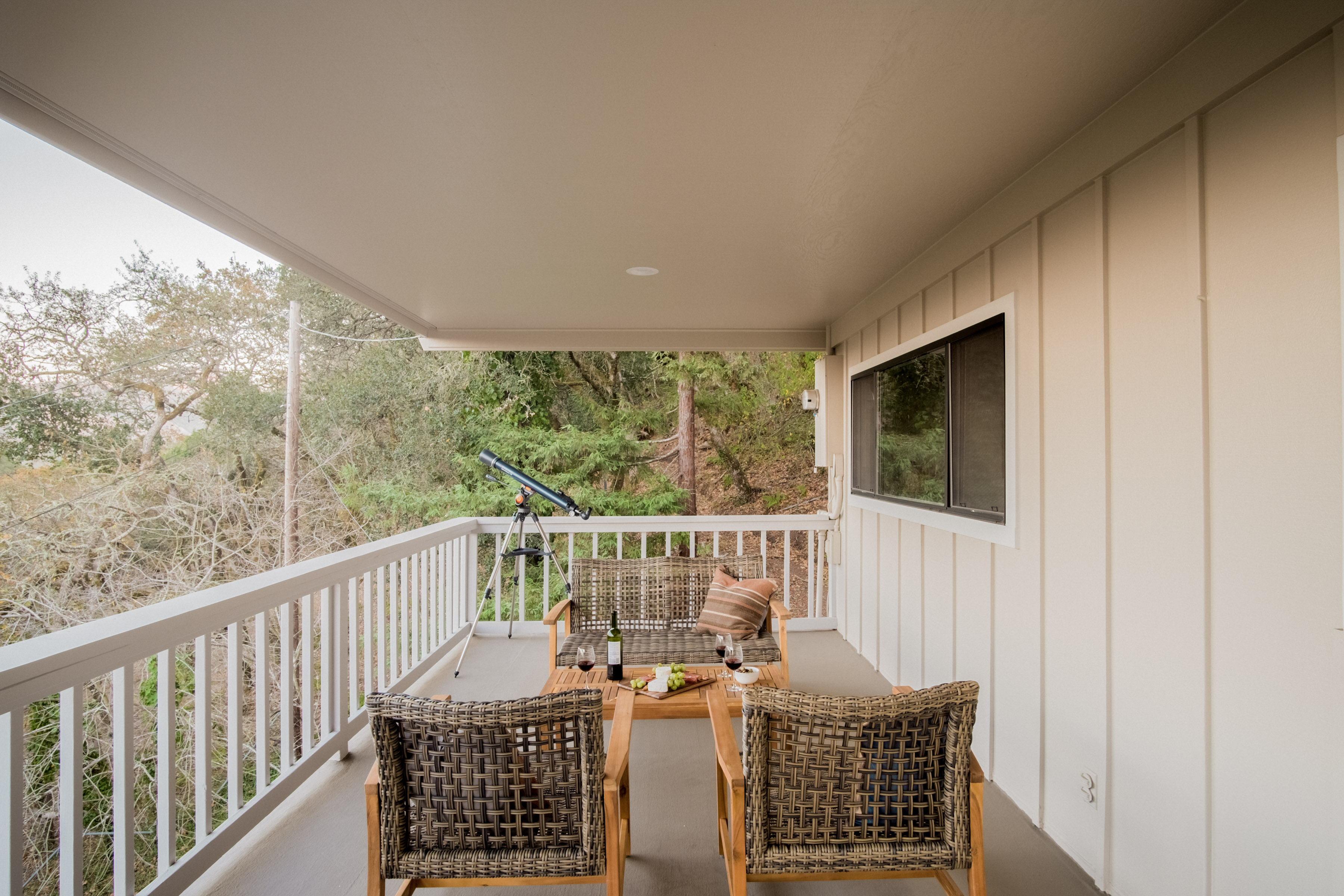 Covered balcony with treetop views, cozy seating, and a telescope
