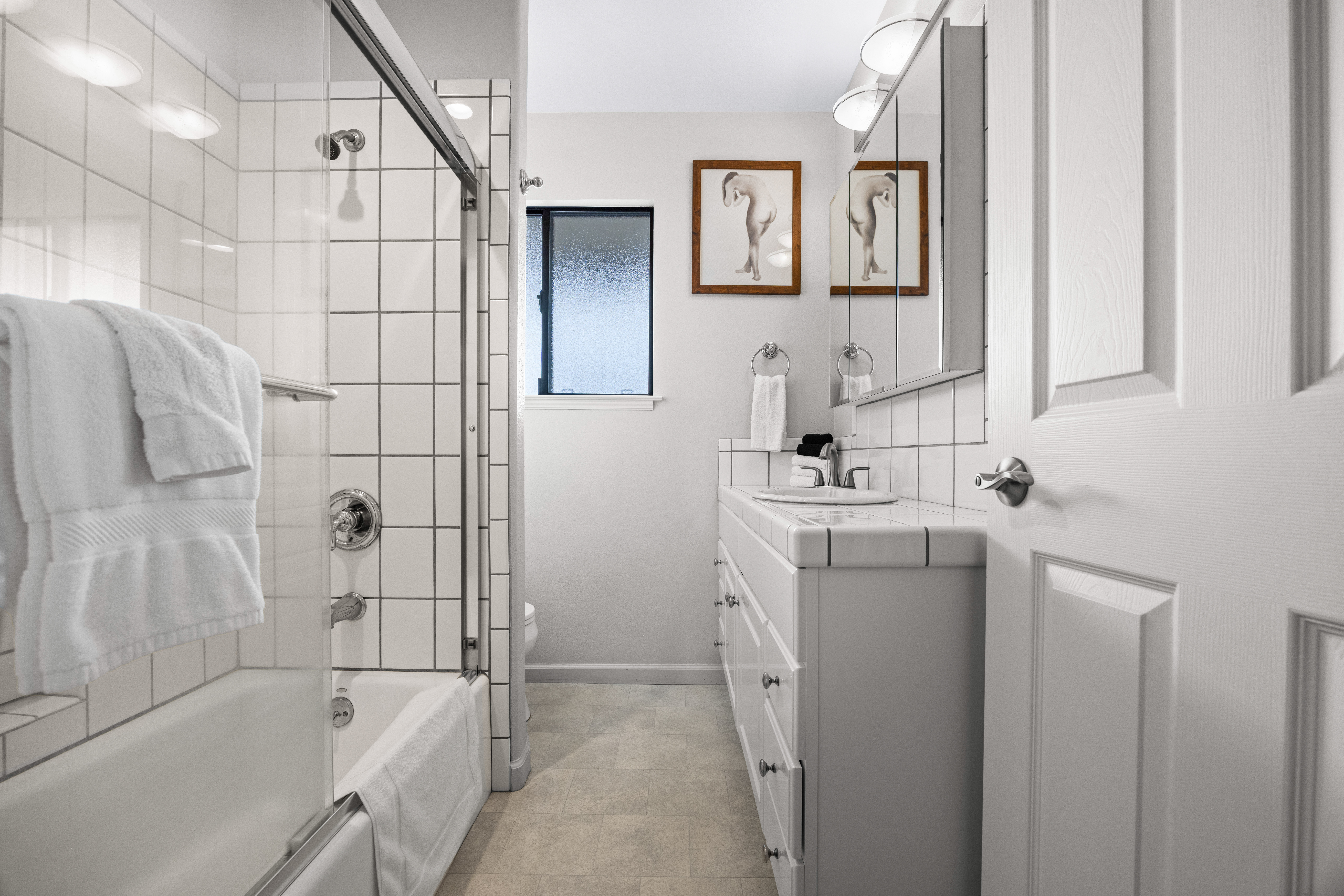 Bright, spotless bathroom with tiled shower-tub and modern vanity