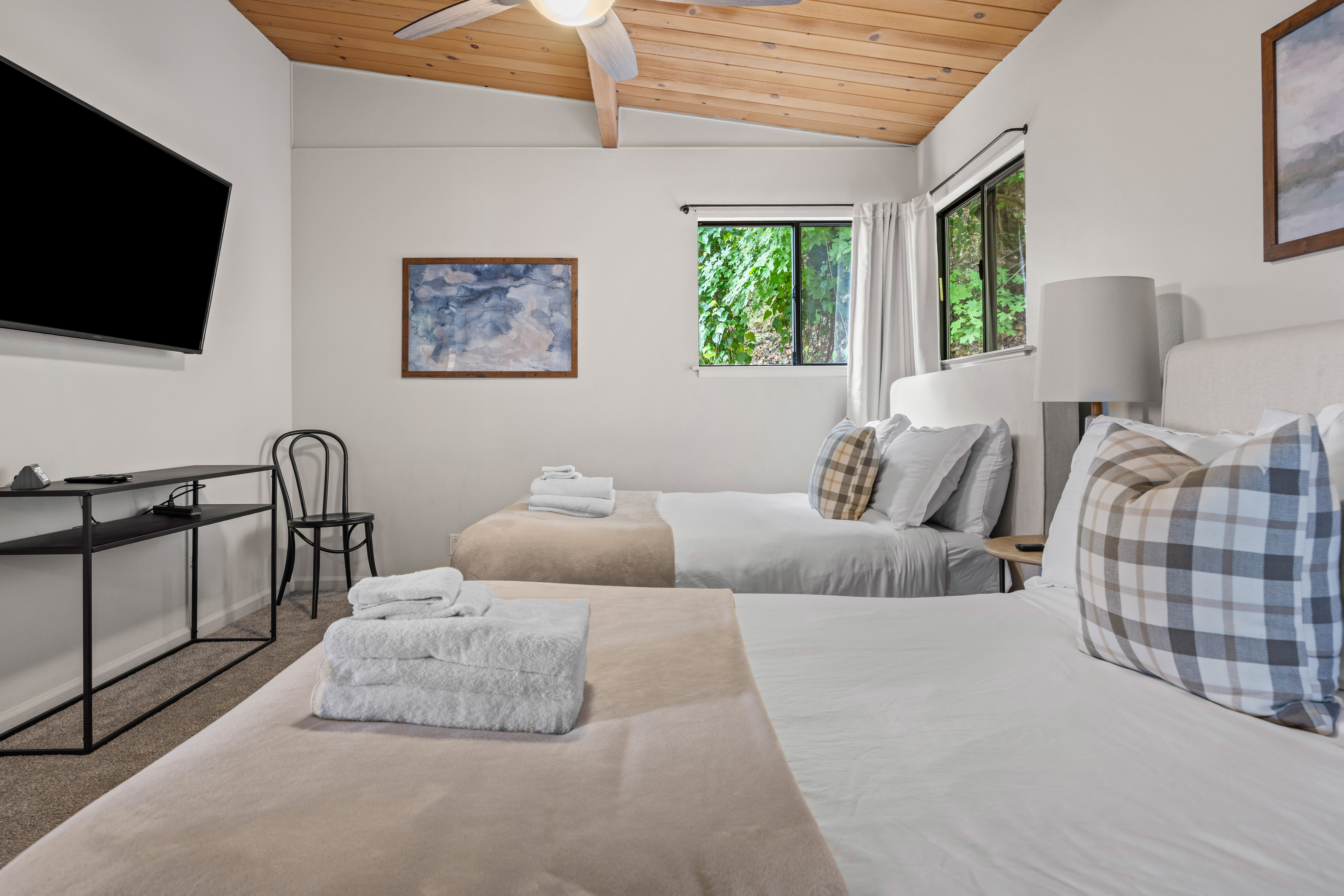 Bright double bedroom with vaulted wood ceilings and leafy views