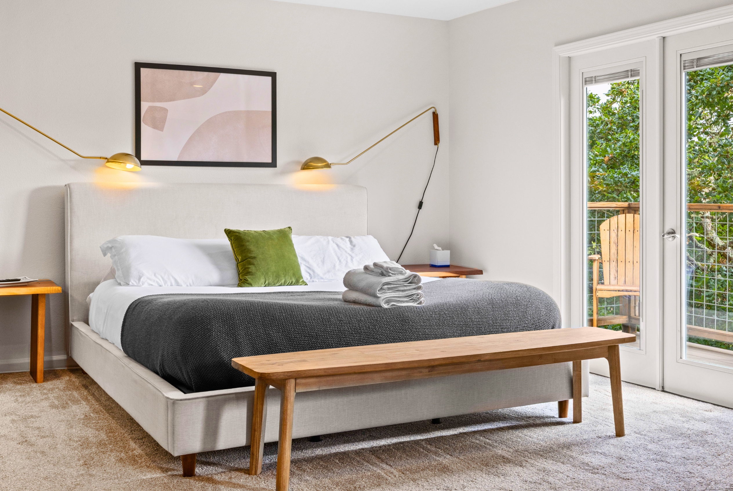 Bright modern bedroom with private balcony, reading lights, and leafy views