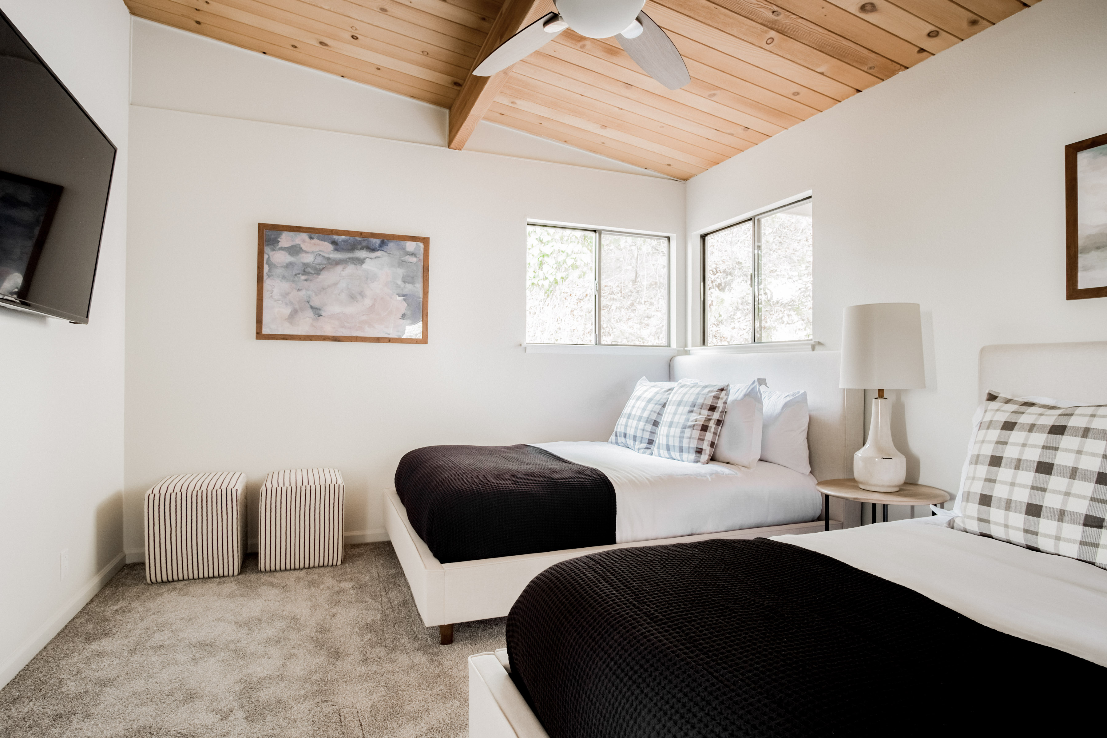 Bright twin bedroom with vaulted wood ceilings, natural light, and cozy modern style