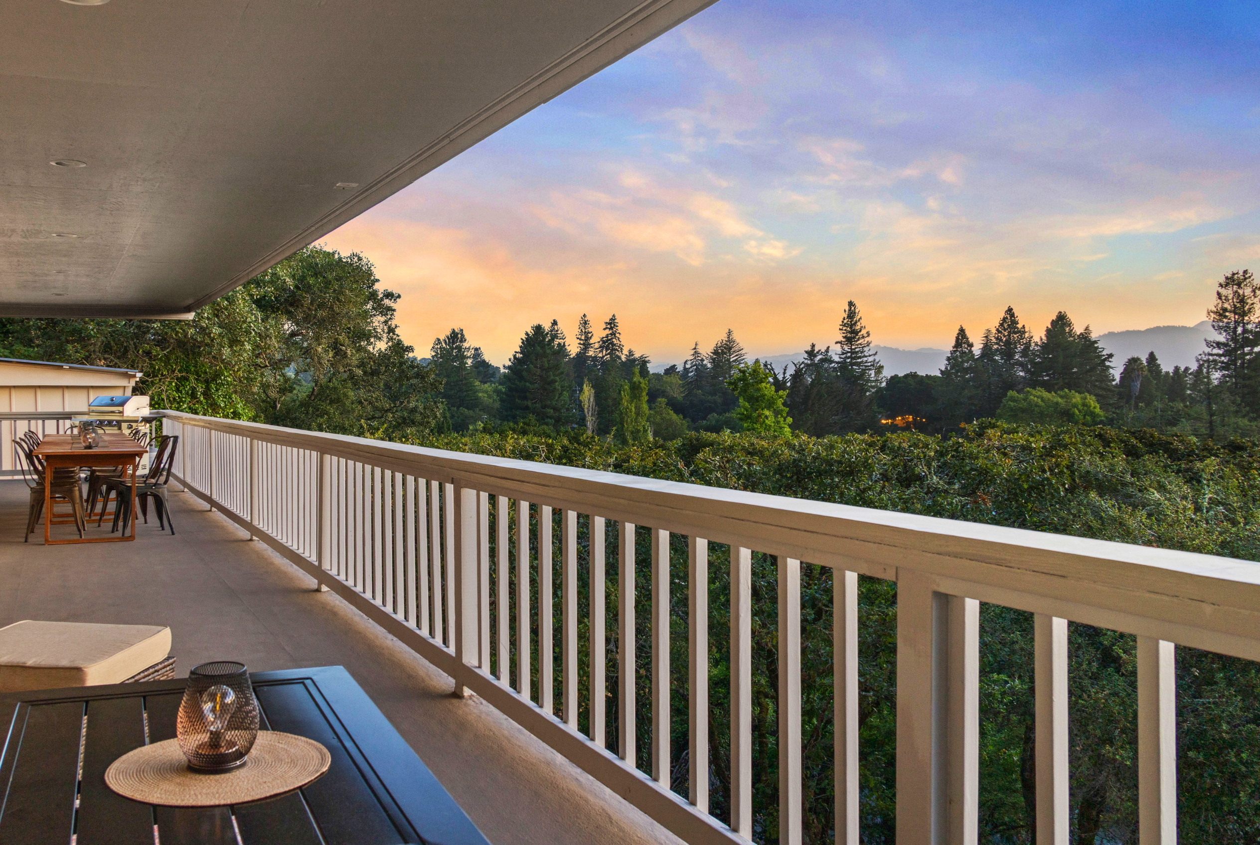 Spacious sunset-view balcony with dining area and treetop vistas