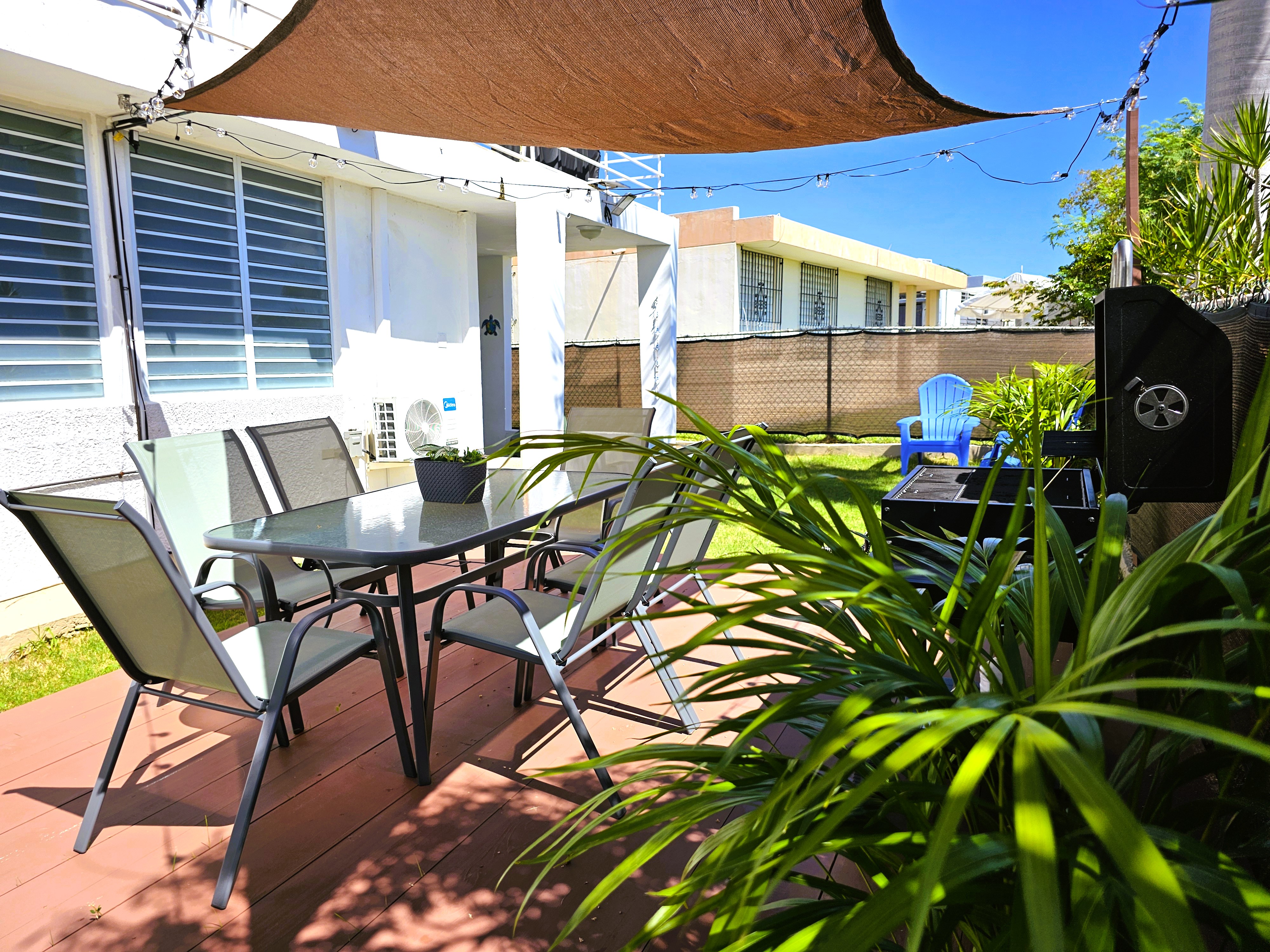 Shaded backyard patio with dining for 6, grill, and tropical greenery