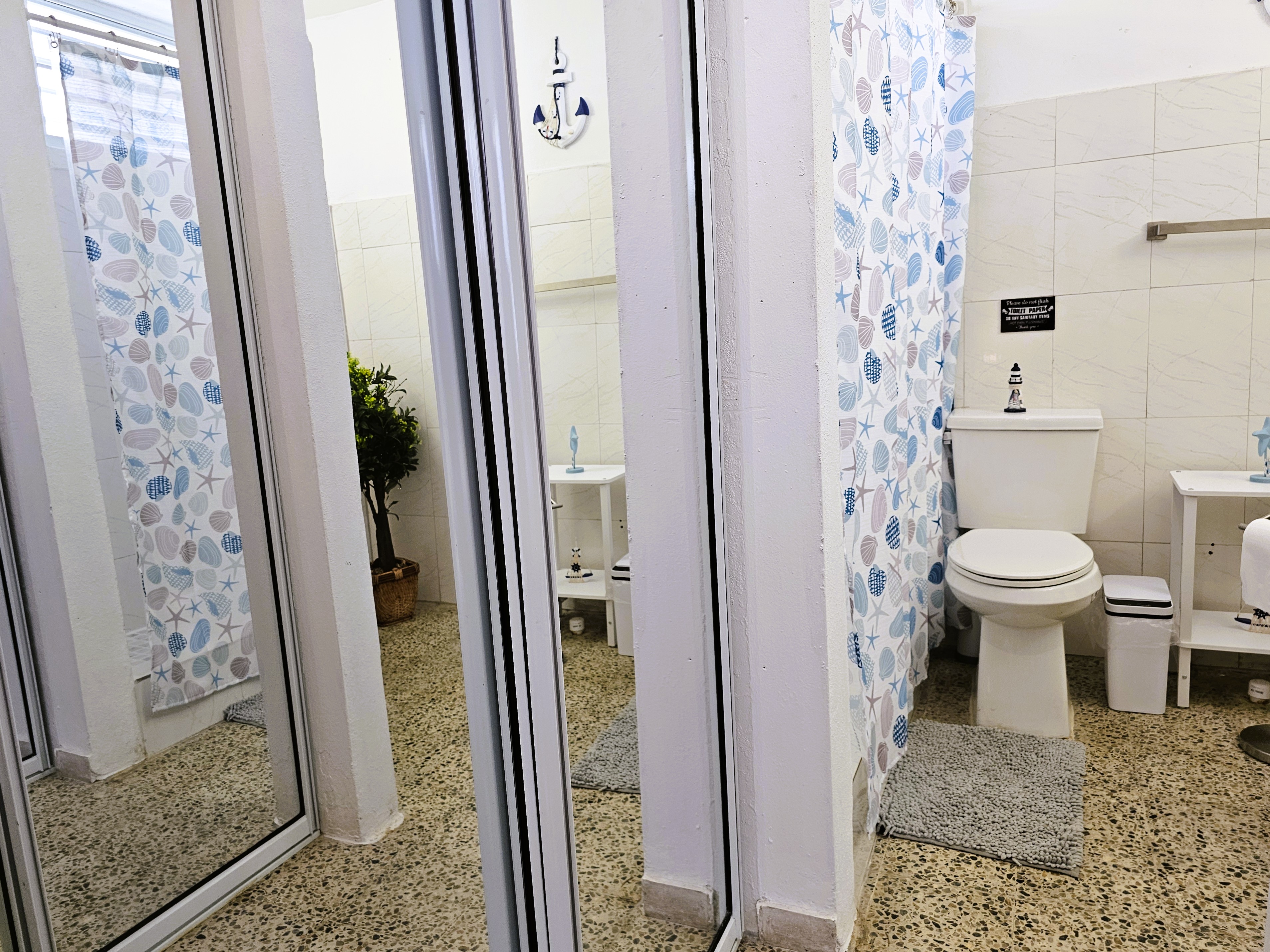 Bright bathroom with mirrored doors and coastal-style shower curtains