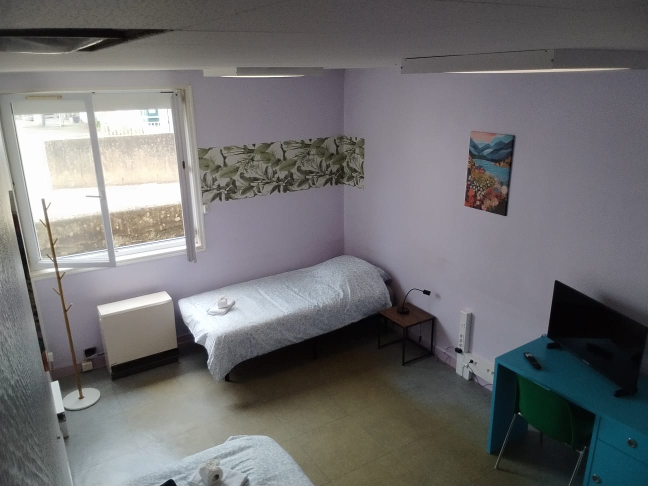 Bright twin room with natural light, TV, and simple cozy setup