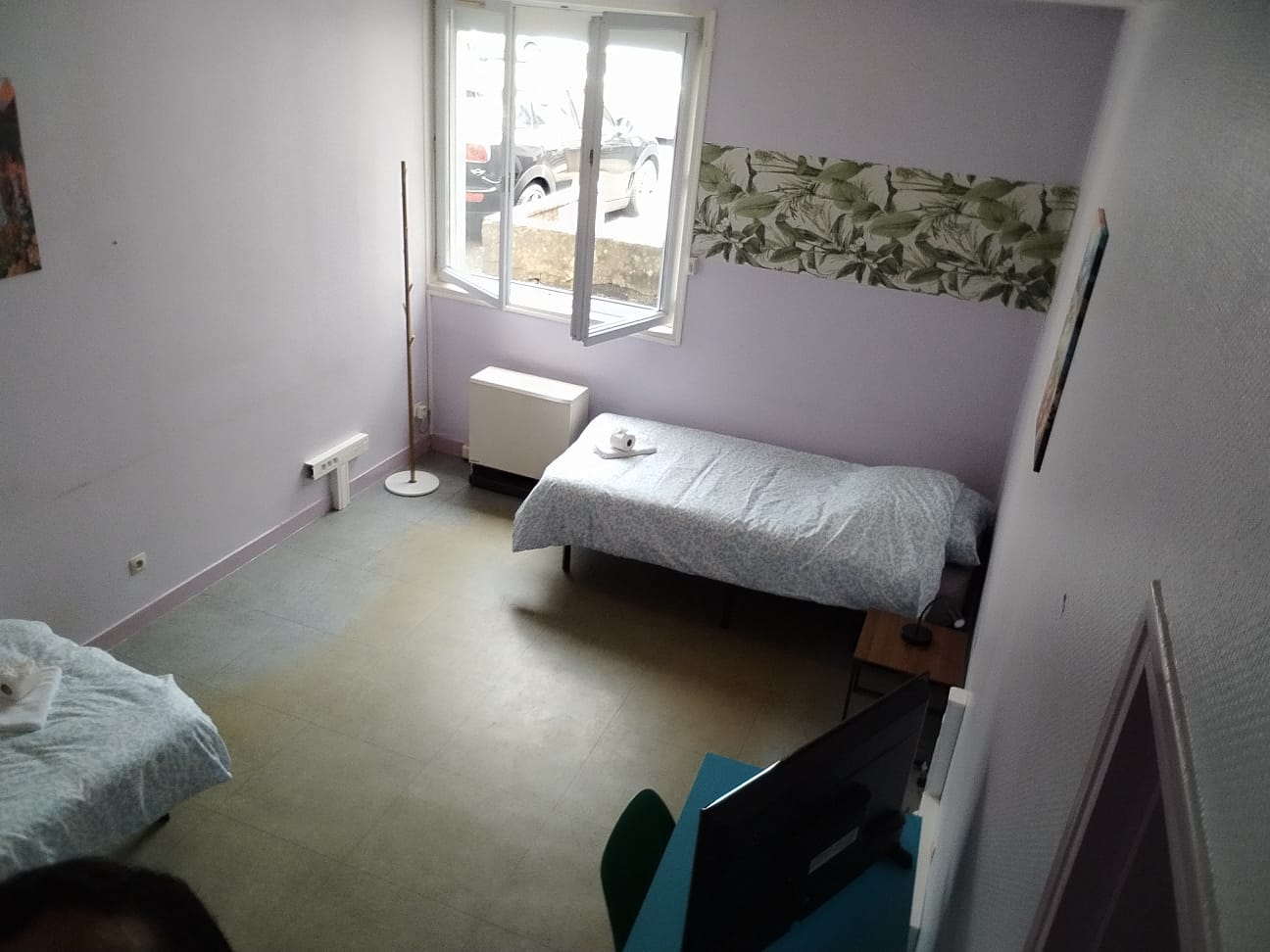 Bright twin room with natural light, TV, and simple modern comfort