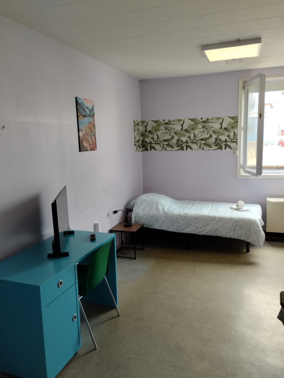 Bright single room with desk, TV, and natural light
