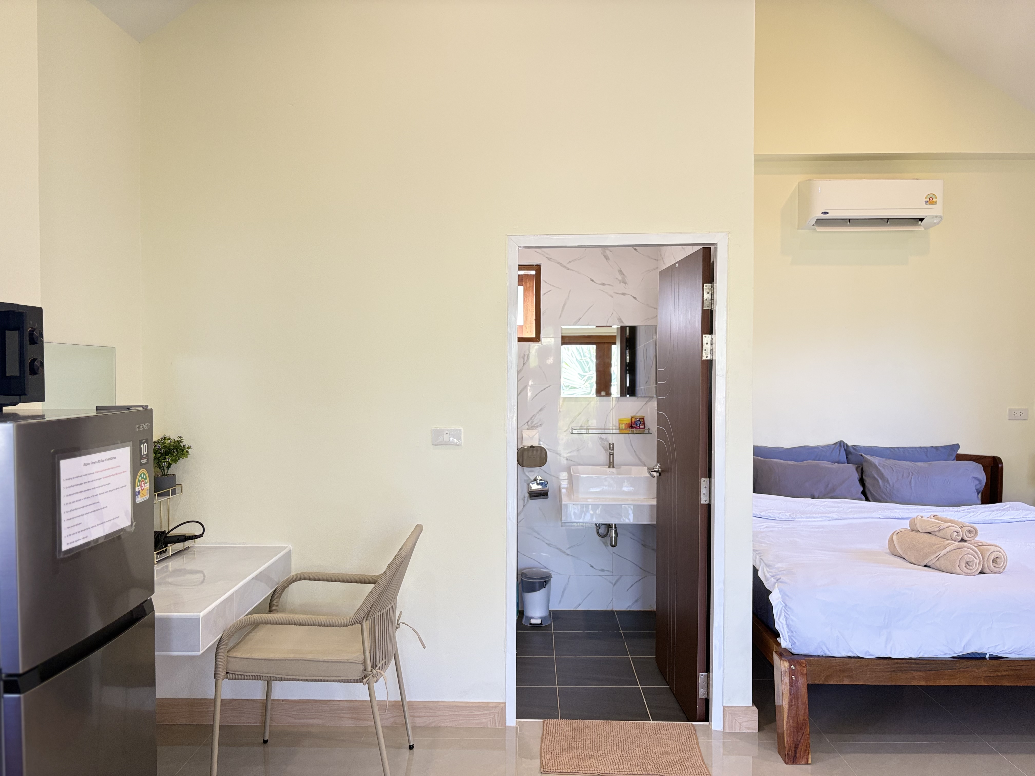 Bright studio room with ensuite bath, AC, desk, and mini fridge