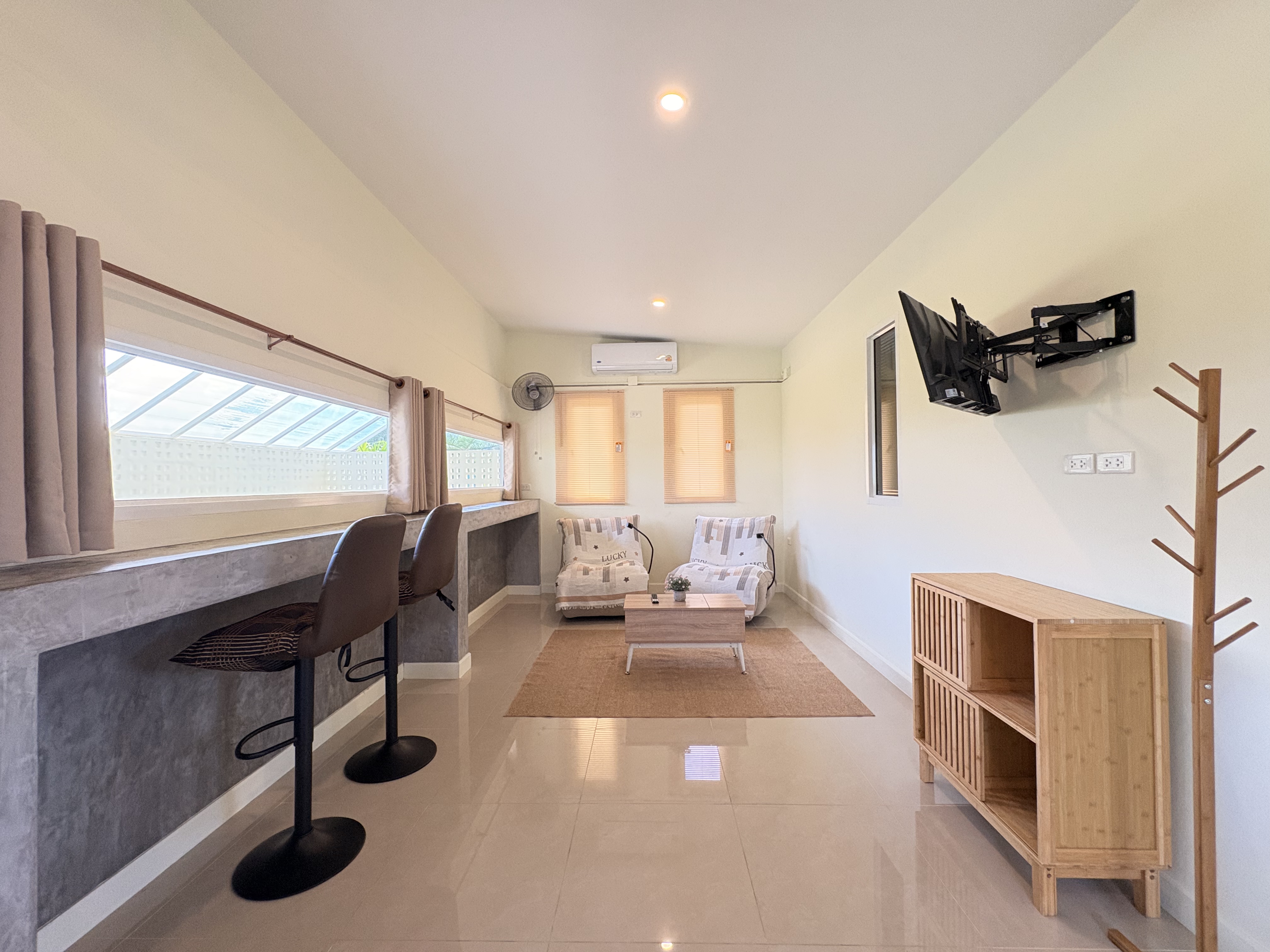 Bright minimalist lounge with bar seating, AC, and a cozy TV area