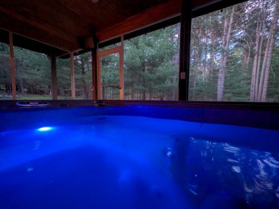 Hot tub lit up at night with views into the pines