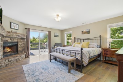 Spacious king bedroom with stone fireplace and private deck access