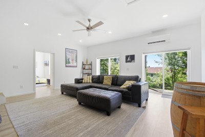 Bright open living room with large windows, comfy sectional, and treetop views