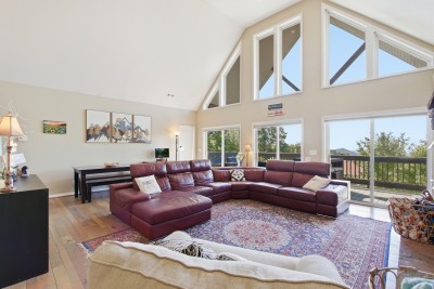 Bright vaulted living room with large sectional and scenic view deck