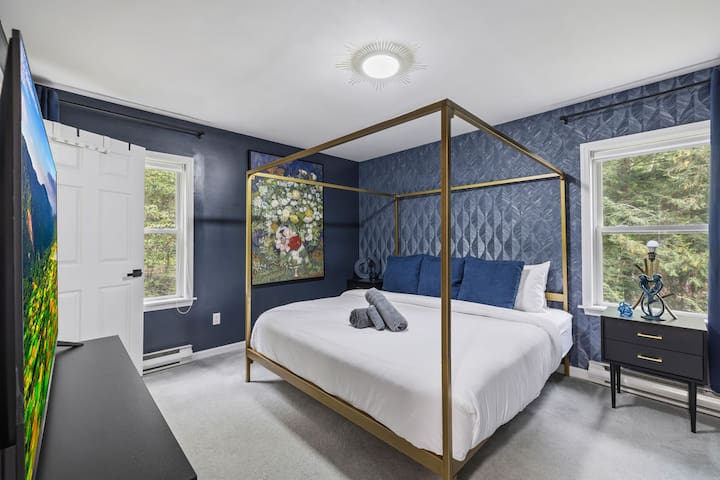 Elegant navy bedroom with gold canopy bed and bright garden-view windows