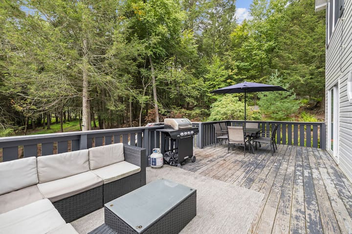 Private wooded deck with lounge seating, grill, and outdoor dining