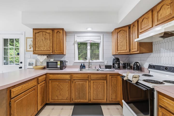 Bright kitchen with ample counter space, full appliances, and sunny window views