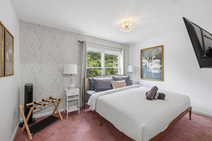 Bright, elegant bedroom with TV, plush bed, and peaceful garden views