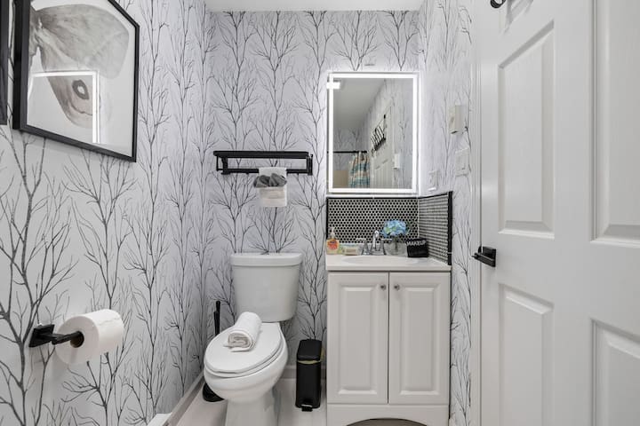 Stylish bathroom with bold wallpaper, modern vanity, and glowing mirror