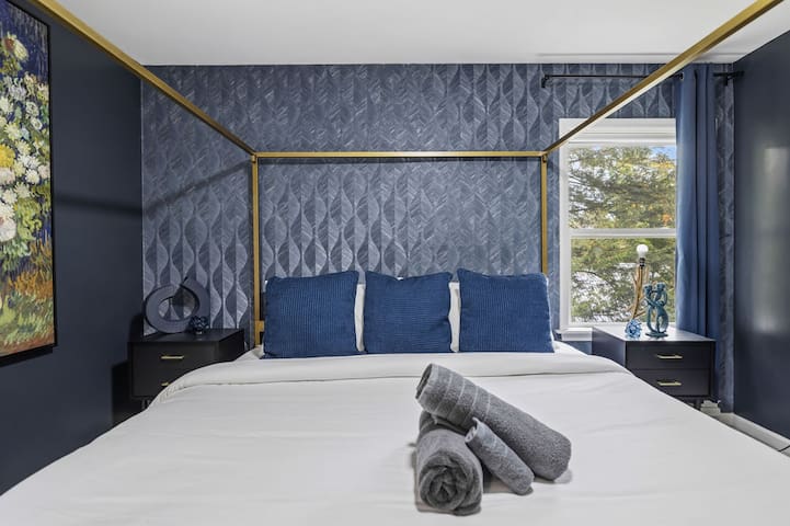 Elegant four-poster bedroom with bold blue design and boutique-style charm