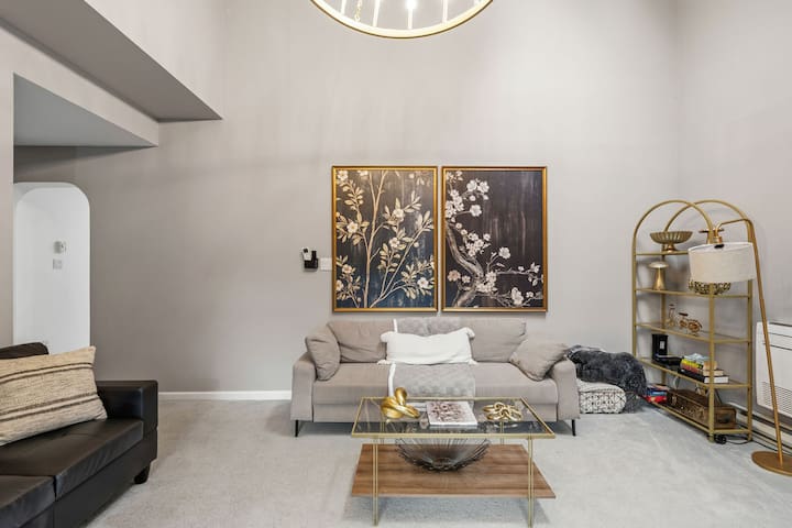 Elegant living room with high ceilings, gold accents, and cozy seating