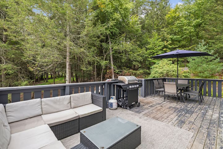 Private wooded deck with lounge seating, grill, and outdoor dining